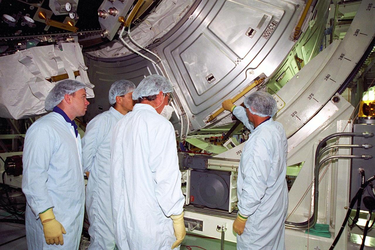 Astronauts Scott J. Kelly and Piers J. Sellers join STS-88 Mission Specialist Jerry L. Ross and a Boeing technician in inspecting the Unity connecting module, part of the International Space Station, at the Space Station Processing Facility at KSC. The Unity connecting module will be mated to the Zarya control module, which will already be in orbit. The STS-88 crew is participating in a Crew Equipment Interface Test (CEIT), which gives astronauts an opportunity for a hands-on look at the payloads on which they will be working while on orbit. STS-88 will be the first Space Shuttle launch for the International Space Station. Launch is scheduled for December 1998