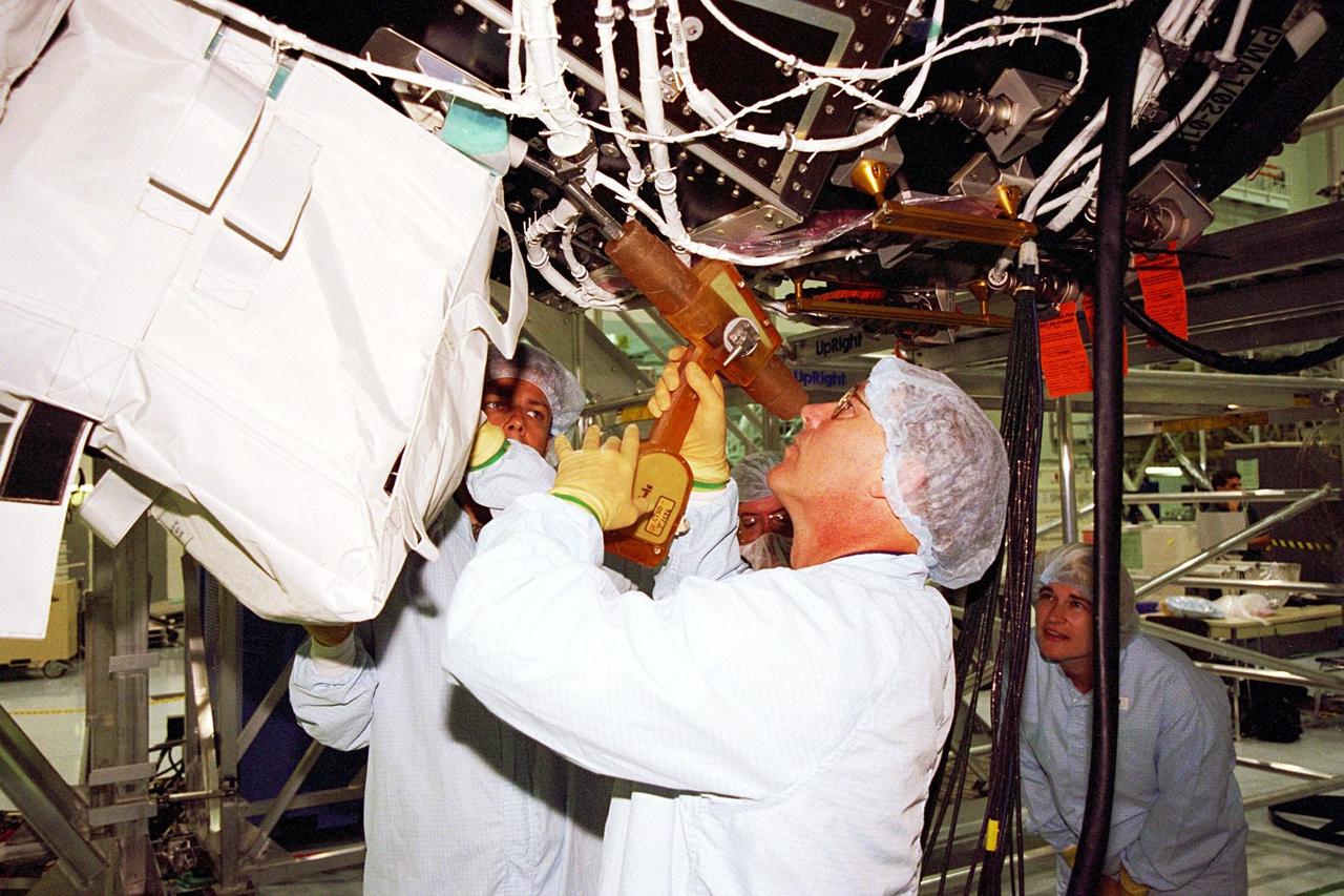KENNEDY SPACE CENTER, FLA. -- STS-88 Mission Specialist Jerry L. Ross (center) removes the cover from the Unity connecting module, part of the International Space Station, so that he and Boeing Technician Doug Adams (left) can inspect it. Training Technician Glenda Laws (right) watches the procedure. The STS-88 crew is participating in the Crew Equipment Interface Test (CEIT) held in the Space Station Processing Facility. The CEIT gives astronauts an opportunity for a hands-on look at the payloads on which they will be working while on orbit. STS-88 will be the first Space Shuttle launch for the International Space Station. Launch is scheduled for December 1998