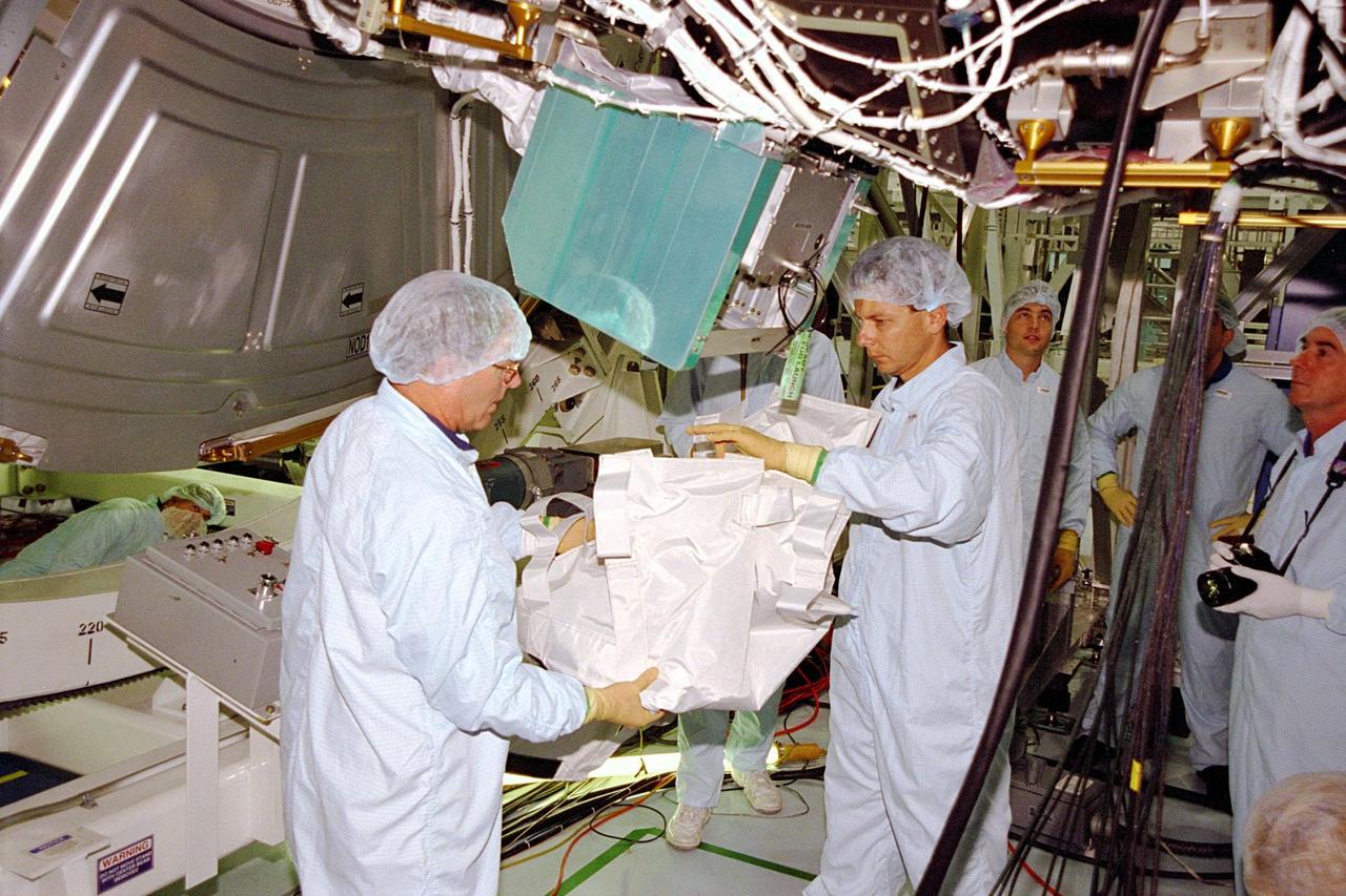 KENNEDY SPACE CENTER, FLA. -- STS-88 Mission Specialist Jerry L. Ross removes a cover from the Unity connecting module, part of the International Space Station, while other crew members and technicians watch. The Unity will be mated to the Zarya control module, which will already be in orbit. The STS-88 crew is participating in the Crew Equipment Interface Test (CEIT) held in the Space Station Processing Facility. The CEIT gives astronauts an opportunity for a hands-on look at the payloads on which they will be working while on orbit. STS-88 will be the first Space Shuttle launch for the International Space Station. Launch is scheduled for December 1998