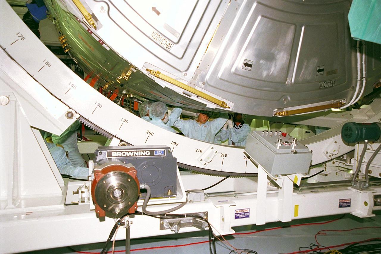 KENNEDY SPACE CENTER, FLA. -- STS-88 crew members and technicians get under the Unity connecting module to examine it during a Crew Equipment Interface Test (CEIT) in the Space Station Processing Facility at KSC. The Unity connecting module is part of the International Space Station, and during the mission, will be mated to the Zarya control module, which will already be in orbit. The CEIT gives astronauts an opportunity for a hands-on look at the payloads on which they will be working while on orbit. STS-88 will be the first Space Shuttle launch for the International Space Station. Launch is scheduled for December 1998