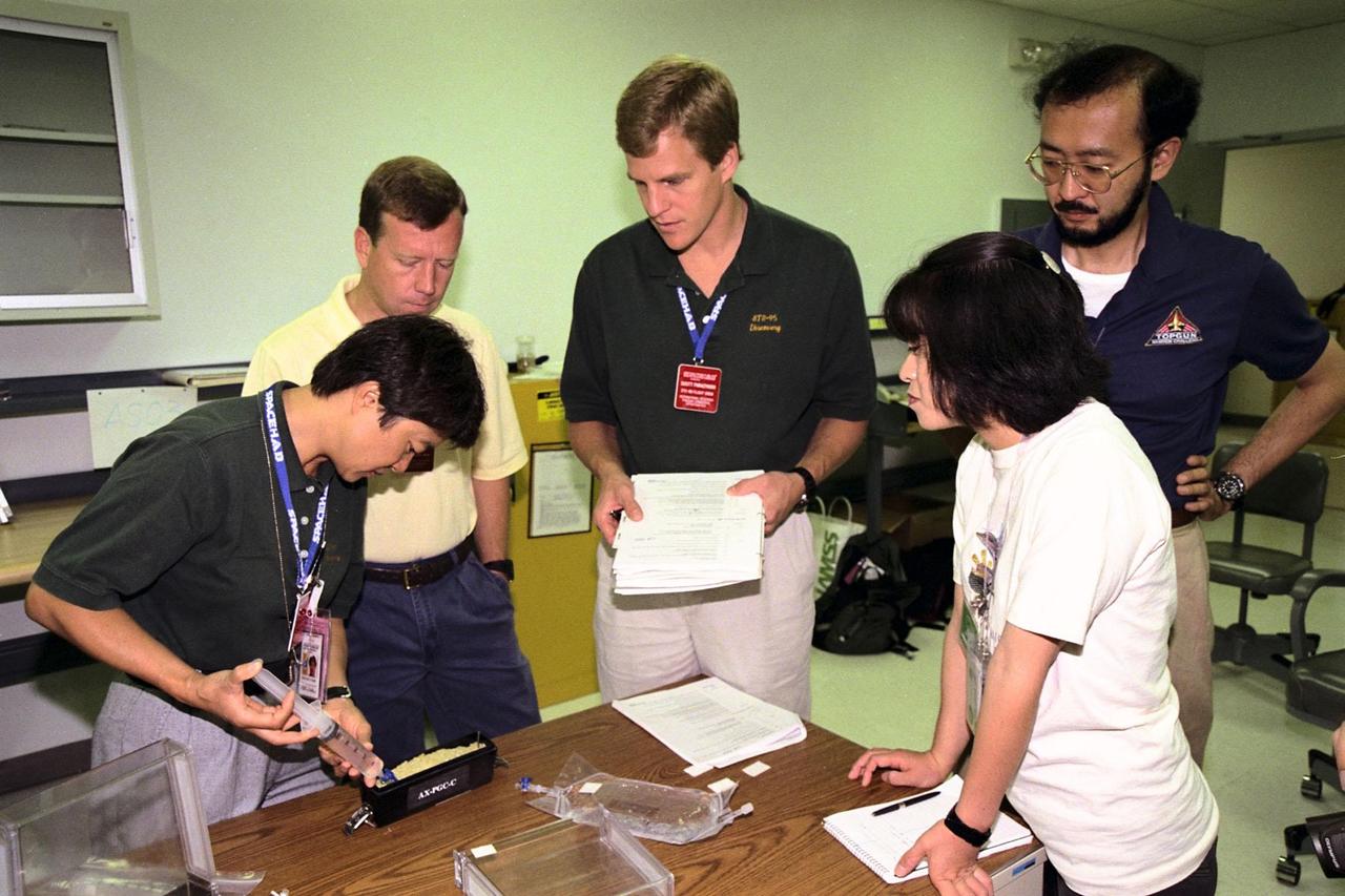 STS-95 Payload Specialist Chiaki Mukai, at far left, of the National Space Development Agency of Japan (NASDA) works on the Biological Research in Canisters (BRIC) experiment which will fly on the scheduled nine-day mission. Watching her, starting with second from left, are STS-95 Pilot Steven W. Lindsey, Mission Specialist Scott E. Parazynski, and NASDA representatives Sachiko Aizawa and Shigeki Kamigaichi. STS-95 will feature a variety of research payloads, including the Spartan solar-observing deployable spacecraft, the Hubble Space Telescope Orbital Systems Platform, the International Extreme Ultraviolet Hitchhiker, and experiments on space flight and the aging process. STS-95 is targeted for an Oct. 29 launch aboard the Space Shuttle Discovery