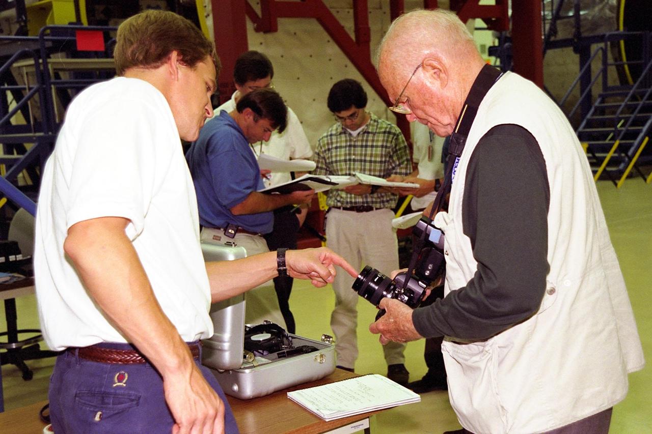 KENNEDY SPACE CENTER, FLA. -- STS-95 Payload Specialist John H. Glenn Jr., at right, and Mission Specialist Scott E. Parazynski examine a camera at the SPACEHAB Payload Processing Facility in Cape Canaveral. STS-95 will feature a variety of research payloads, including the Spartan solar-observing deployable spacecraft, the Hubble Space Telescope Orbital Systems Platform, the International Extreme Ultraviolet Hitchhiker, and experiments on space flight and the aging process. STS-95 is targeted for an Oct. 29 launch aboard the Space Shuttle Discovery