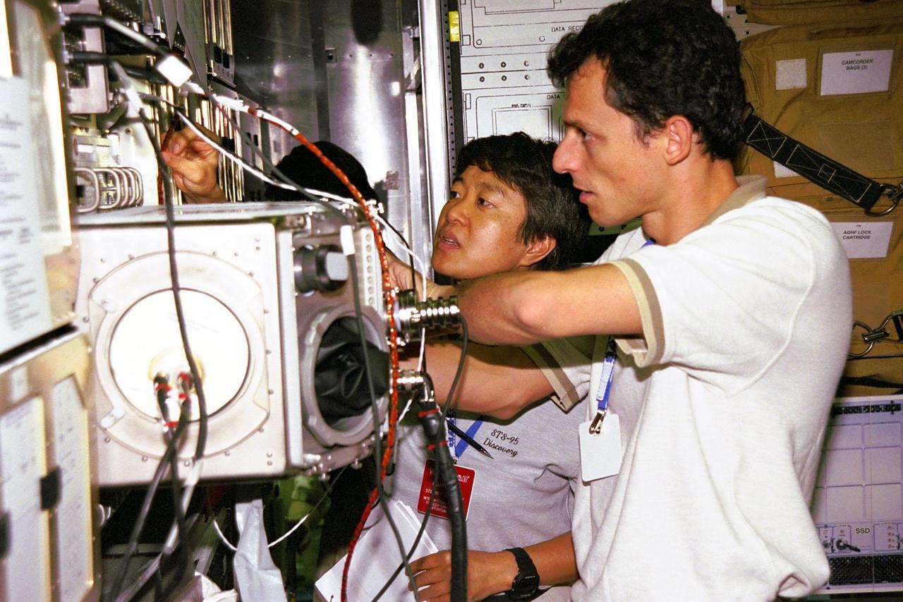 KENNEDY SPACE CENTER, F LA. -- STS-95 Payload Specialists Chiaki Mukai, at left, representing the National Space Development Agency of Japan (NASDA), and Mission Specialist Pedro Duque of Spain, representing the European Space Agency (ESA), practice using equipment in the SPACEHAB trainer at the SPACEHAB Payload Processing Facility in Cape Canaveral. STS-95 will feature a variety of research payloads, including the Spartan solar-observing deployable spacecraft, the Hubble Space Telescope Orbital Systems Platform, the International Extreme Ultraviolet Hitchhiker, and experiments on space flight and the aging process. STS-95 is targeted for an Oct. 29 launch aboard the Space Shuttle Discovery.
