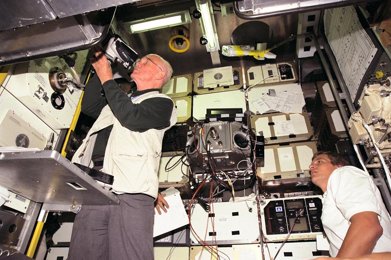 KENNEDY SPACE CENTER, FLA. -- STS-95 Payload Specialist John H. Glenn Jr., who also is a senator from Ohio, adjusts a a video camera in the SPACEHAB trainer at the SPACEHAB Payload Processing Facility in Cape Canaveral. Mission Specialist Scott E. Parazynski looks on at right. STS-95 will feature a variety of research payloads, including the Spartan solar-observing deployable spacecraft, the Hubble Space Telescope Orbital Systems Platform, the International Extreme Ultraviolet Hitchhiker, and experiments on space flight and the aging process. STS-95 is targeted for an Oct. 29 launch aboard the Space Shuttle Discovery