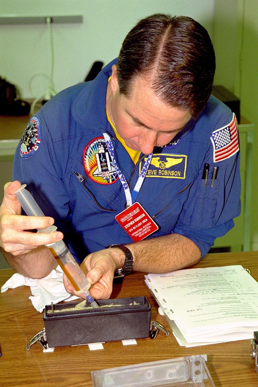 KENNEDY SPACE CENTER, FLA. -- STS-95 Mission Specialist Stephen K. Robinson injects water into the base of the seed container where plants will grow during the upcoming mission. This is part of the Biological Research in Canisters (BRIC) experiment which is at the SPACEHAB Payload Processing Facility, Cape Canaveral, Fla. This experiment will fly in SPACEHAB in Discovery’s payload bay. STS-95 is scheduled to launch from pad 39B at KSC on Oct. 29, 1998. The mission also includes research payloads such as the Spartan solar-observing deployable spacecraft, the Hubble Space Telescope Orbital Systems Test Platform, the International Extreme Ultraviolet Hitchhiker, as well as experiments on space flight and the aging process