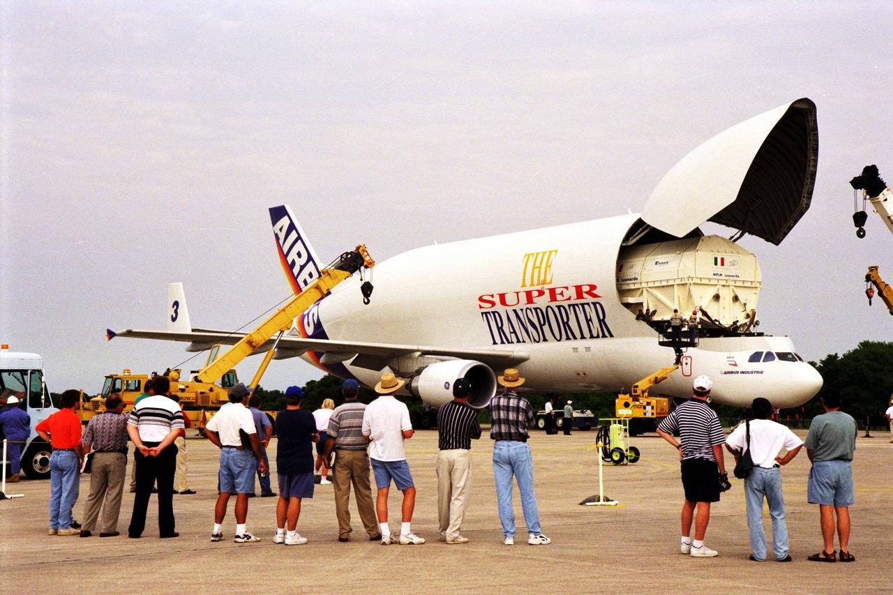 KENNEDY SPACE CENTER, FLA. -- KSC personnel watch as workers at the Shuttle Landing Facility begin unloading the canister containing the Multi-Purpose Logistics Module (MPLM), the Leonardo, from the Airbus Beluga transporter. Leonardo is scheduled to be launched on STS-100 in December 1999. The modules are being provided by Alenia Aerospazio, in Italy, and will be operated by NASA and supported by ASI, the Italian space agency. The MPLMs will be carried in the payload bay of a Shuttle orbiter, and will provide storage and additional work space for up to two astronauts when docked to the International Space Station. The second MPLM, to be handed over in April 1999, is named Raffaello. A third module, to be named Donatello, is due to be delivered in October 2000 for launch in January 2001