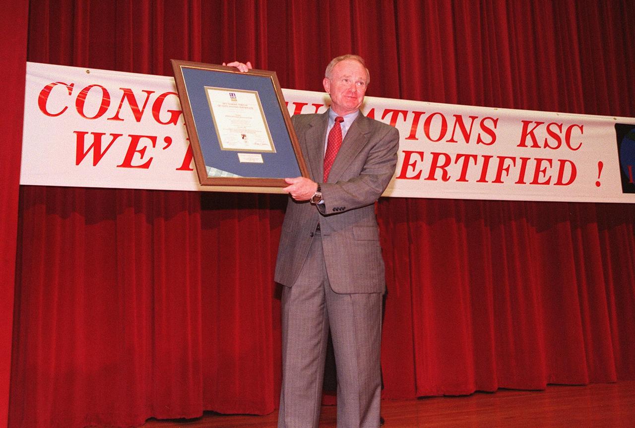 Center Director Roy Bridges displays the ISO 9001 certificate he was awarded by Det Norske Veritas (DNV), Inc., an international ISO certification organization, at a ceremony at KSC. Dalton Lyon of DNV made the presentation, which included a 2000th ISO Certificate Plaque. ISO 9001 comprises the most detailed, comprehensive set of standard requirements for quality programs established by the International Standards Organization. The presentation followed a successful independent audit by DNV of the KSC Management System in May of this year. The third-party auditors examined about 20 elements of KSC's system, including management responsibility, design control, documentation, test and inspection, and corrective action procedures. DNV found that KSC met or exceeded the stringent quality standards in all areas. KSC will use this certification as a tool to improve an already world-class team. All NASA centers are required by NASA Administrator Daniel S. Goldin to be ISO 9001 registered by September 1999. NASA is the first federal agency to seek the quality certification