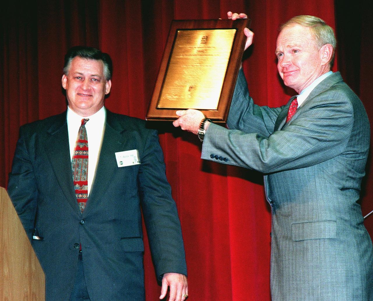Center Director Roy Bridges (right) displays the 2000th ISO Certificate Plaque he was given by Dalton Lyon (left) of Det Norske Veritas (DNV), Inc., an international ISO certification organization, at a ceremony at KSC. The plaque is a representation of the ISO 9001 certification awarded to KSC by DNV. ISO 9001 comprises the most detailed, comprehensive set of standard requirements for quality programs established by the International Standards Organization. The presentation followed a successful independent audit by DNV of the KSC Management System in May of this year. The third-party auditors examined about 20 elements of KSC's system, including management responsibility, design control, documentation, test and inspection, and corrective action procedures. DNV found that KSC met or exceeded the stringent quality standards in all areas. KSC will use this certification as a tool to improve an already worldclass team. All NASA centers are required by NASA Administrator Daniel S. Goldin to be ISO 9001 registered by September 1999. NASA is the first federal agency to seek the quality certification