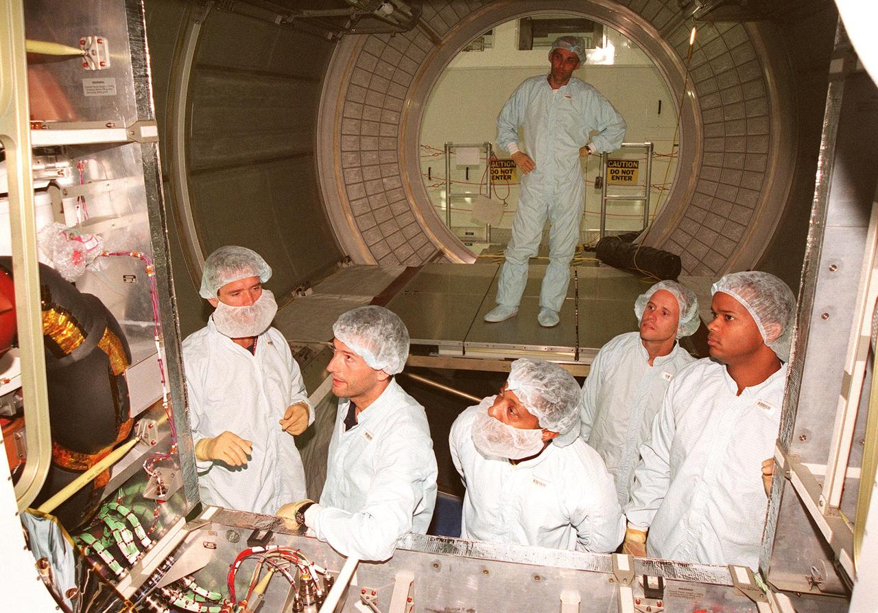 STS-100 Mission Specialist Chris Hadfield (Canada), Salimbeti Andrea (of Alenia Aerospazio), observers Astronaut Winston Scott and Scott McIntyre, and Mission Specialist Robert Curbeam take a close look at the opening of the Multi-Purpose Logistics Module (MPLM) that will be launched on STS-100 on Dec. 2, 1999. Behind them is Paolo Prato , a systems engineer with Alenia. The MPLM will be carried in the payload bay of the Shuttle orbiter, and will provide storage and additional work space for up to two astronauts when docked to the International Space Station. Named Leonardo, the MPLM is the first of three modules being provided by Alenia Aerospazio. The second MPLM, to be handed over in April 1999, is named Raffaello. A third module, to be named Donatello, is due to be delivered in October 2000 for launch in January 2001