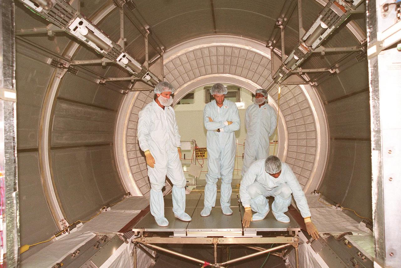 (Left to right) STS-100 Mission Specialist Chris Hadfield, Salimbeti Andrea of Alenia Aerospazio, observer Astronaut Winston Scott, and Mission Specialist Robert Curbeam examine the interior of the Multi-Purpose Logistics Module (MPLM) Leonardo. The Italian-built MPLM will be carried in the payload bay of the Shuttle orbiter, and will provide storage and additional work space for up to two astronauts when docked to the International Space Station. It is expected to fly on the Space Shuttle Endeavour scheduled for launch on Dec. 2, 1999. Leonardo is the first of three modules being provided by Alenia. The second MPLM, to be handed over in April 1999, is named Raffaello. A third module, to be named Donatello, is due to be delivered in October 2000 for launch in January 2001