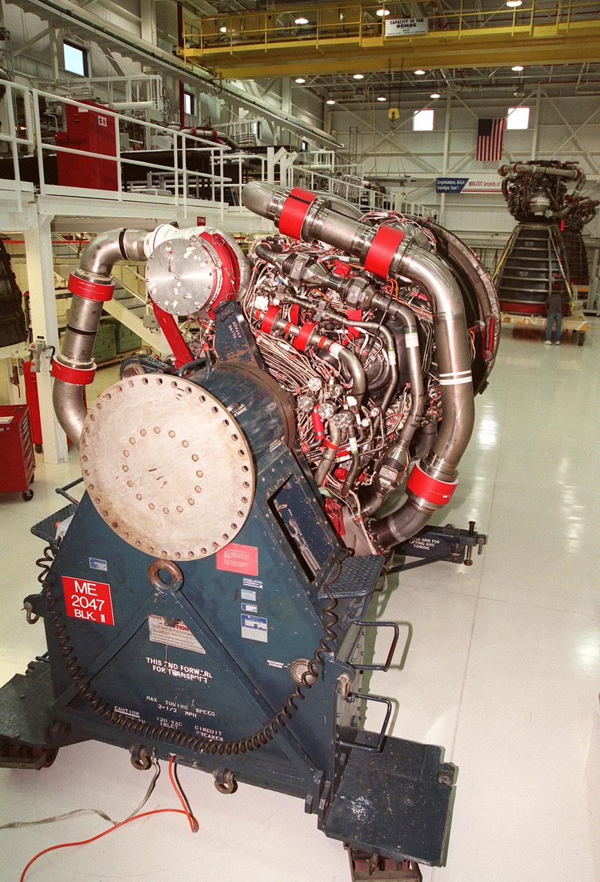 In the Space Shuttle Main Engine Processing Facility (SSMEPF), a new Block 2A engine sits on the transport cradle before being moved to the workstand. The engine is scheduled to fly on the Space Shuttle Endeavour during the STS-88 mission in December 1998. The SSMEPF officially opened on July 6, replacing the Shuttle Main Engine Shop