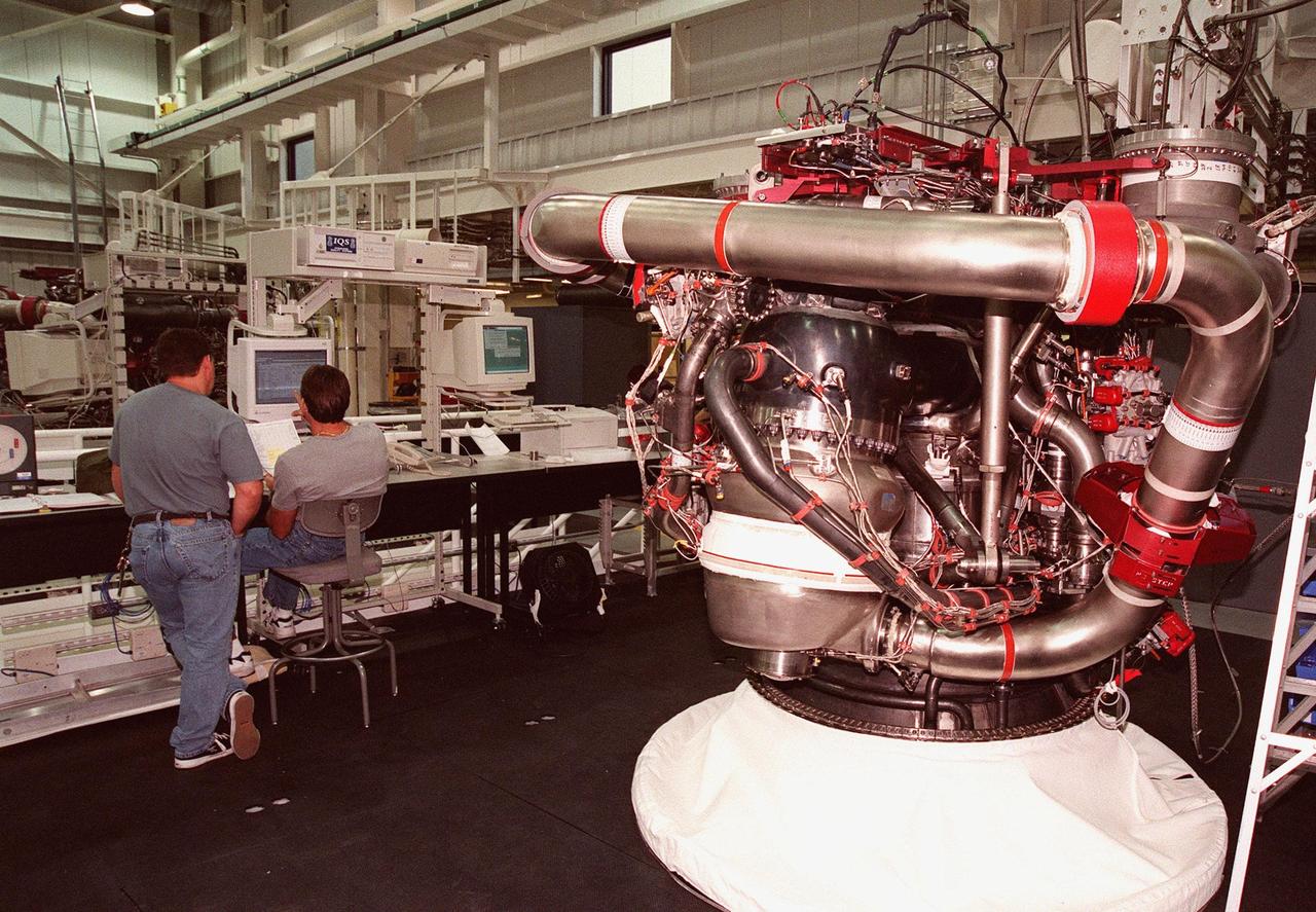 In the Space Shuttle Main Engine Processing Facility (SSMEPF), a new Block 2A engine sits on the workstand as technicians process it. The engine is scheduled to fly on the Space Shuttle Endeavour during the STS-88 mission in December 1998. The SSMEPF officially opened on July 6, replacing the Shuttle Main Engine Shop