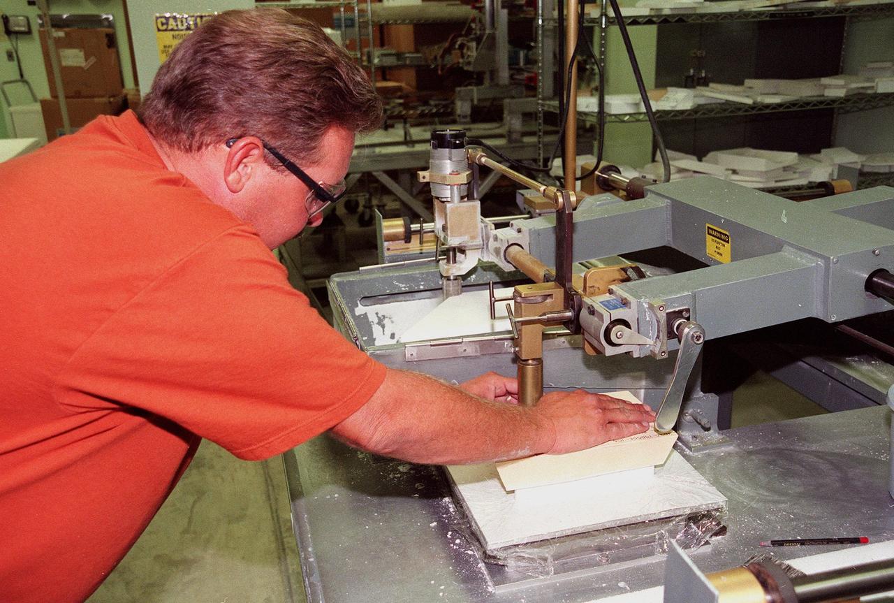 In the Tile Fabrication Shop, Tony Rollins, with United Space Alliance, cuts a High-Temperature Reusable Surface Insulation (HRSI) tile on a gun stock contour milling machine. About 70 percent of a Space Shuttle orbiter’s external surface is shielded from heat by a network of more than 24,000 tiles formed from a silica fiber compound. HRSI tiles cover the lower surface of the orbiter, areas around the forward windows, upper body flap, the base heat shield, the "eyeballs" on the front of the Orbital Maneuvering System (OMS) pods, and the leading and trailing edges of the vertical stabilizer and the rudder speed brake. They are generally 6 inches square, but may also be as large as 12 inches square in some areas, and 1 to 5 inches thick. More advanced materials such as Flexible Insulation Blankets have replaced tiles on some upper surfaces of the orbiter