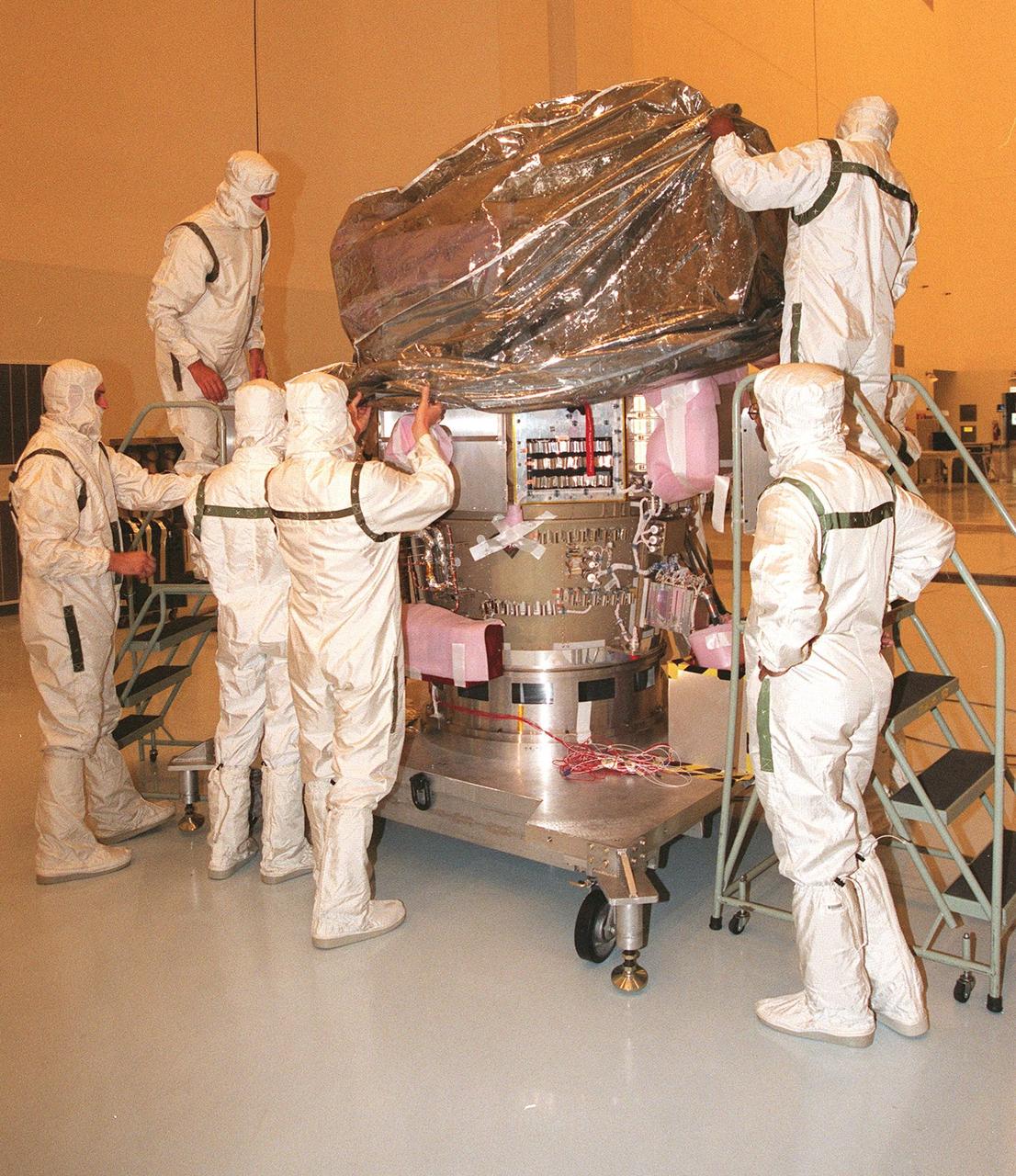 KENNEDY SPACE CENTER, FLA. -- Wearing special protective suits, workers remove the protective covering from NASA’s Deep Space 1 spacecraft in the Payload Hazardous Servicing Facility at KSC to prepare it for prelaunch processing. Targeted for launch on a Boeing Delta 7326 rocket on Oct. 15, 1998, the first flight in NASA’s New Millennium Program is designed to validate 12 new technologies for scientific space missions of the next century. Onboard experiments include an ion propulsion engine and software that tracks celestial bodies so the spacecraft can make its own navigation decisions without the intervention of ground controllers. Deep Space 1 will complete most of its mission objectives within the first two months, but will also do a flyby of a near-Earth asteroid, 1992 KD, in July 1999