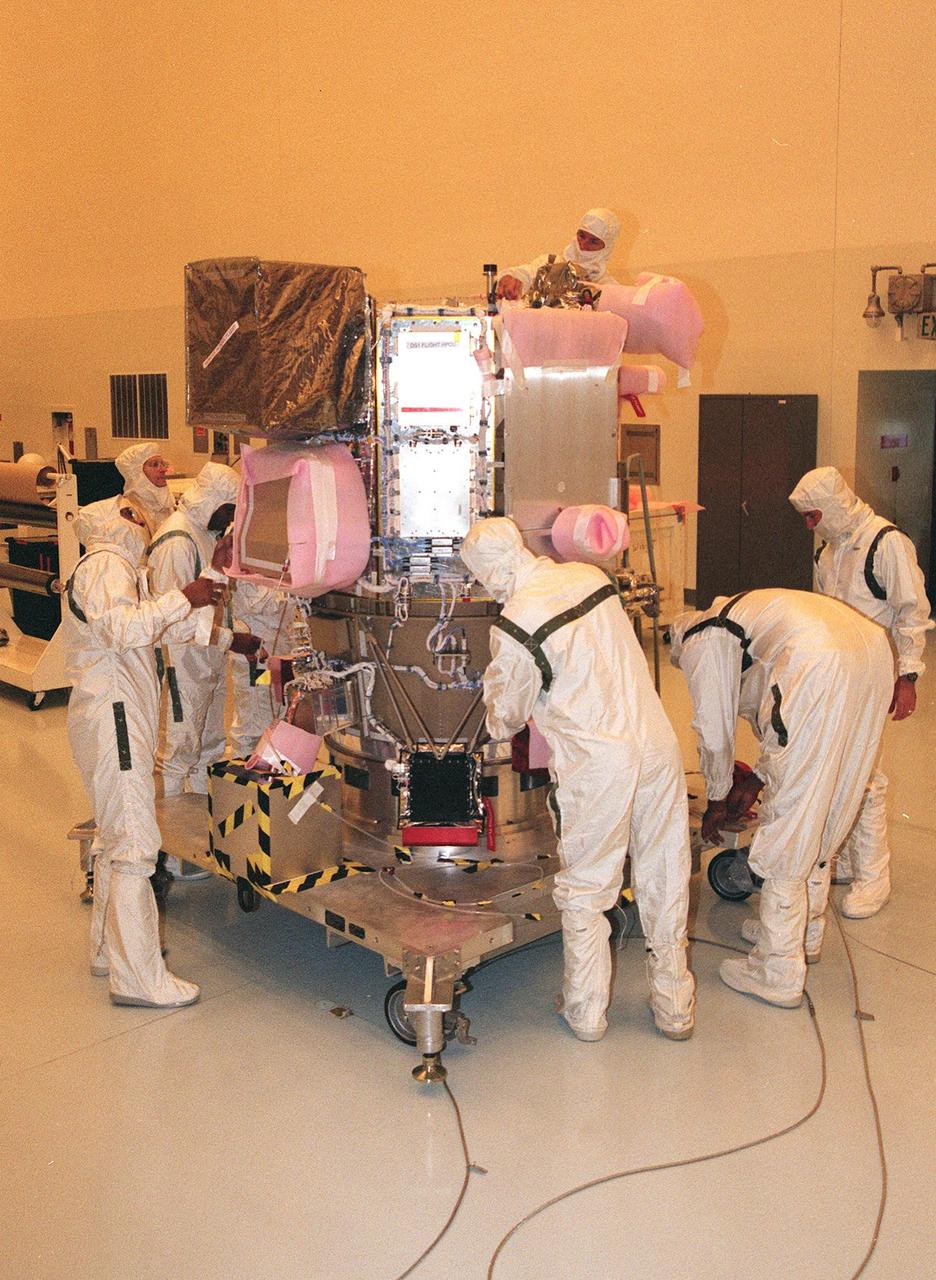 KENNEDY SPACE CENTER, FLA. -- Wearing special protective suits, workers ready NASA’s Deep Space 1 spacecraft for prelaunch processing in the Payload Hazardous Servicing Facility at KSC. Targeted for launch on a Boeing Delta 7326 rocket on Oct. 15, 1998, the first flight in NASA’s New Millennium Program is designed to validate 12 new technologies for scientific space missions of the next century. Onboard experiments include an ion propulsion engine and software that tracks celestial bodies so the spacecraft can make its own navigation decisions without the intervention of ground controllers. Deep Space 1 will complete most of its mission objectives within the first two months, but will also do a flyby of a near-Earth asteroid, 1992 KD, in July 1999