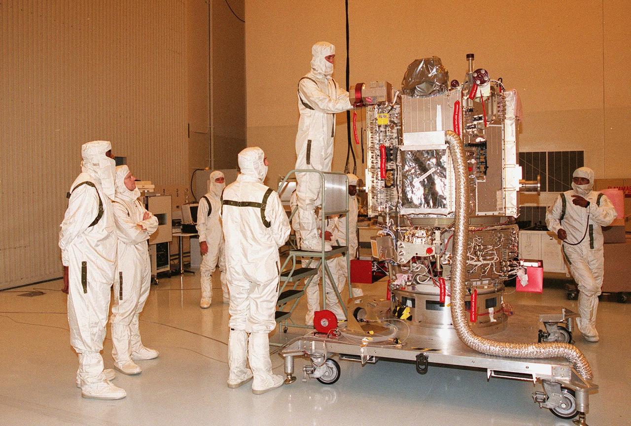 KENNEDY SPACE CENTER, FLA. -- Wearing special protective suits, workers ready NASA’s Deep Space 1 spacecraft for prelaunch processing in the Payload Hazardous Servicing Facility at KSC. Targeted for launch on a Boeing Delta 7326 rocket on Oct. 15, 1998, the first flight in NASA’s New Millennium Program is designed to validate 12 new technologies for scientific space missions of the next century. Onboard experiments include an ion propulsion engine and software that tracks celestial bodies so the spacecraft can make its own navigation decisions without the intervention of ground controllers. Deep Space 1 will complete most of its mission objectives within the first two months, but will also do a flyby of a near-Earth asteroid, 1992 KD, in July 1999