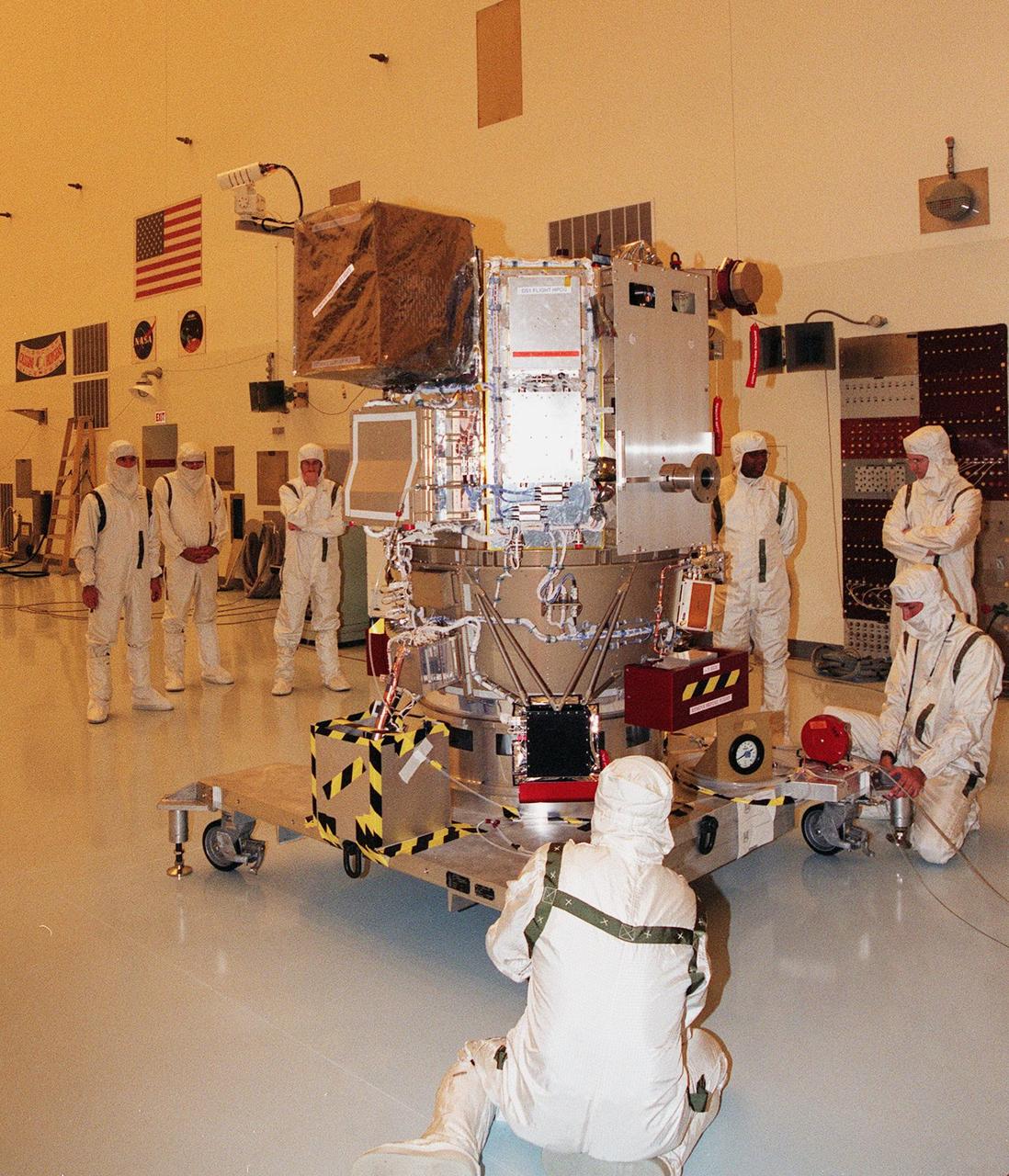 KENNEDY SPACE CENTER, FLA. -- Wearing special protective suits, workers maneuver NASA’s Deep Space 1 spacecraft into place for prelaunch processing in the Payload Hazardous Servicing Facility at KSC. Targeted for launch on a Boeing Delta 7326 rocket on Oct. 15, 1998, the first flight in NASA’s New Millennium Program is designed to validate 12 new technologies for scientific space missions of the next century. Onboard experiments include an ion propulsion engine and software that tracks celestial bodies so the spacecraft can make its own navigation decisions without the intervention of ground controllers. Deep Space 1 will complete most of its mission objectives within the first two months, but will also do a flyby of a near-Earth asteroid, 1992 KD, in July 1999