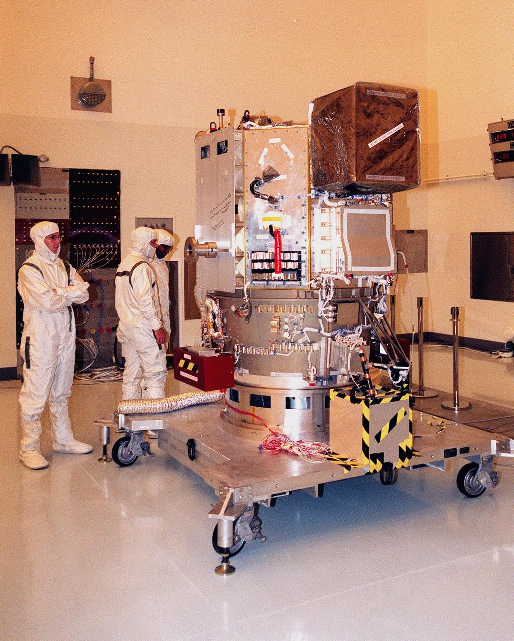 KENNEDY SPACE CENTER, FLA. -- Wearing special protective suits, workers look over NASA’s Deep Space 1 spacecraft before prelaunch processing in the Payload Hazardous Servicing Facility at KSC. Targeted for launch on a Boeing Delta 7326 rocket on Oct. 15, 1998, the first flight in NASA’s New Millennium Program is designed to validate 12 new technologies for scientific space missions of the next century. Onboard experiments include an ion propulsion engine and software that tracks celestial bodies so the spacecraft can make its own navigation decisions without the intervention of ground controllers. Deep Space 1 will complete most of its mission objectives within the first two months, but will also do a flyby of a near-Earth asteroid, 1992 KD, in July 1999