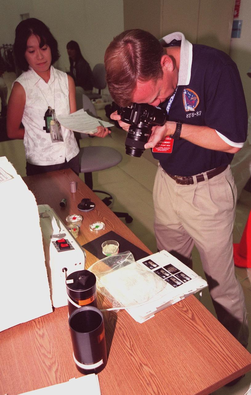 KENNEDY SPACE CENTER, FLA. -- In the SPACEHAB Payload Processing Facility (SPPF), Cape Canaveral, STS-95 Pilot Steven Lindsey (right) photographs BRIC (Biological Research in Canisters) experiments while a representative of the National Space Agency of Japan (NASDA) looks on. Lindsey, along with other crew members, have been participating in SPACEHAB familiarization in the SPPF. The mission, scheduled to launch Oct. 29, includes research payloads such as the Spartan solar-observing deployable spacecraft, the Hubble Space Telescope Orbital Systems Test Platform, the International Extreme Ultraviolet Hitchhiker, as well as the SPACEHAB single module with experiments on space flight and the aging process