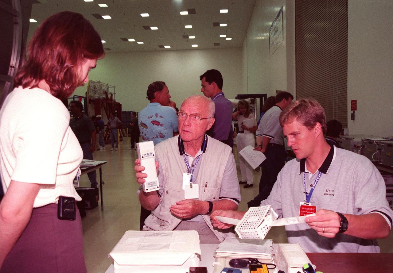 In the SPACEHAB Payload Processing Facility (SPPF), STS-95 KENNEDY SPACE CENTER, FLA. -- Payload Specialist John Glenn (center), who is a senator from Ohio, talks with a KSC worker (left) about a piece of equipment that will fly on the mission while Mission Specialist Scott Parazynski, M.D., (right) examines another item . Standing behind Glenn, Mission Specialist Pedro Duque of Spain, who represents the European Space Agency (ESA), talks with another worker. STS-95 crew members have been participating in SPACEHAB familiarization in the SPPF. Scheduled to launch Oct. 29, the mission includes research payloads such as the Spartan solar-observing deployable spacecraft, the Hubble Space Telescope Orbital Systems Test Platform, the International Extreme Ultraviolet Hitchhiker, as well as the SPACEHAB single module with experiments on space flight and the aging process