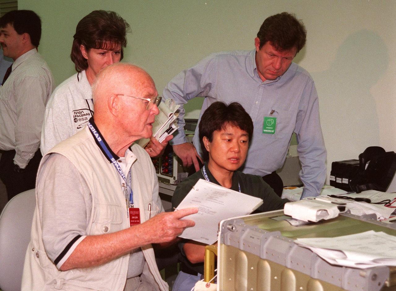 KENNEDY SPACE CENTER, FLA. -- In the SPACEHAB Payload Processing Facility (SPPF), Cape Canaveral, STS-95 Payload Specialist John Glenn (left), who is a senator from Ohio, checks out equipment with Payload Specialist Chiaki Mukai (right), M.D., Ph.D., who represents the National Space Development Agency of Japan (NASDA) while KSC workers watch. STS-95 crew members have been participating in SPACEHAB familiarization in the SPPF. Scheduled to launch Oct. 29, the mission includes research payloads such as the Spartan solar-observing deployable spacecraft, the Hubble Space Telescope Orbital Systems Test Platform, the International Extreme Ultraviolet Hitchhiker, as well as the SPACEHAB single module with experiments on space flight and the aging process