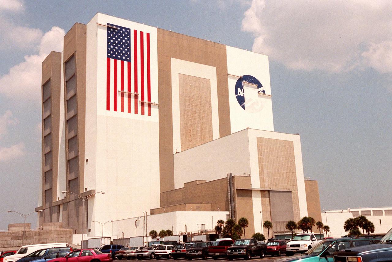 KENNEDY SPACE CENTER, FLA. -- The Vehicle Assembly Building (VAB) gets a facelift with the repainting of the American flag and replacing of the bicentennial emblem with the NASA logo. The painting honors NASA’s 40th anniversary on Oct. 1 and is expected to be complete in mid-September. The flag spans an area 209 feet by 110 feet, or about 23, 437 square feet. Each stripe is 9 feet wide and each star is 6 feet in diameter. The logo, also known as the "meatball," will measure 110 feet by 132 feet, or about 12,300 square feet. Workers, suspended on platforms from the top of the 525-foot-high VAB, are using rollers and brushes to do the painting. The entire fleet of orbiters is also receiving the addition of the NASA logo on their wings and sidewalls