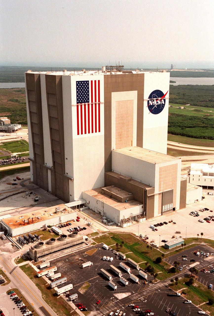 KENNEDY SPACE CENTER, FLA. -- This aerial view shows the Vehicle Assembly Building (VAB) getting a facelift with the repainting of the American flag and replacing of the bicentennial emblem with the NASA logo. The painting honors NASA's 40th anniversary on Oct. 1 and is expected to be complete in mid-September. The flag spans an area 209 feet by 110 feet, or about 23, 437 square feet. Each stripe is 9 feet wide and each star is 6 feet in diameter. The logo, also known as the "meatball," measures 110 feet by 132 feet, or about 12,300 square feet. Workers, suspended on platforms from the top of the 525-foot-high VAB, are using rollers and brushes to do the painting. The entire fleet of orbiters is also receiving the addition of the NASA logo on their wings and sidewalls