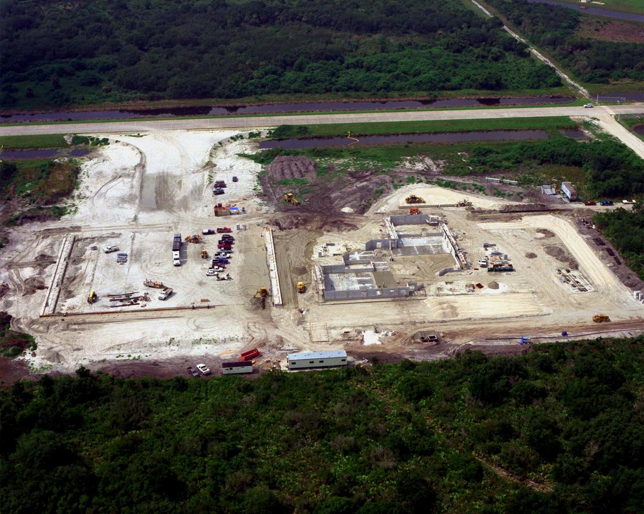 Looking southwest, this view shows ongoing construction of a multi-purpose hangar, which is part of the $8 million Reusable Launch Vehicle (RLV) Support Complex at Kennedy Space Center. Edging the construction is Sharkey Road, which parallels the landing strip of the Shuttle Landing Facility nearby. The RLV complex will include facilities for related ground support equipment and administrative/ technical support. It will be available to accommodate the Space Shuttle; the X-34 RLV technology demonstrator; the L-1011 carrier aircraft for Pegasus and X-34; and other RLV and X-vehicle programs. The complex is jointly funded by the Spaceport Florida Authority, NASA's Space Shuttle Program and KSC. The facility will be operational in early 2000. 