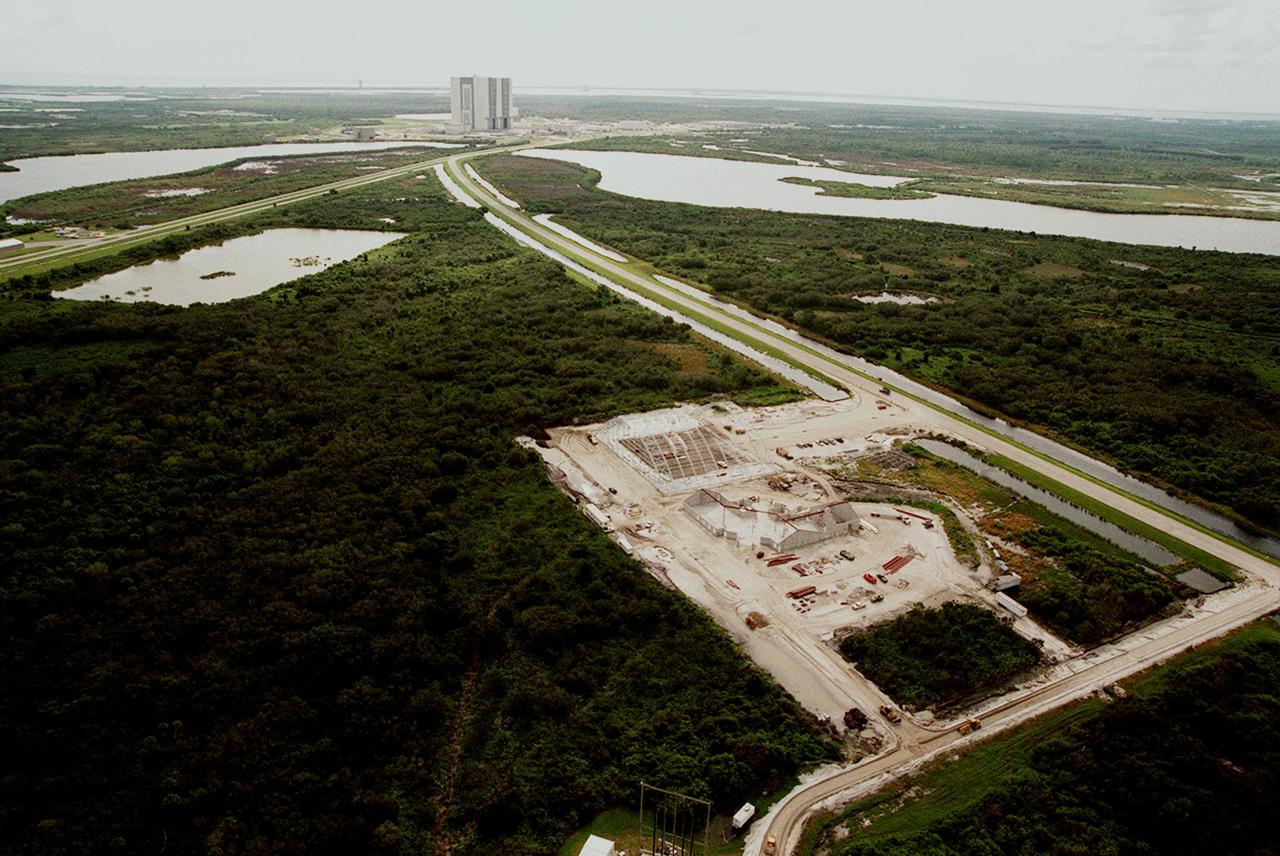 An aerial view reveals (foreground) the ongoing construction of an $8 million Reusable Launch Vehicle (RLV) Support Complex at Kennedy Space Center. At left is a multi-purpose hangar and at right a building for related ground support equipment and administrative/ technical support. In the background is the Vehicle Assembly Building. The road at right is the tow-way. The RLV complex will be available to accommodate the Space Shuttle; the X-34 RLV technology demonstrator; the L-1011 carrier aircraft for Pegasus and X-34; and other RLV and X-vehicle programs. The complex is jointly funded by the Spaceport Florida Authority, NASA's Space Shuttle Program and KSC. The facility will be operational in early 2000. 