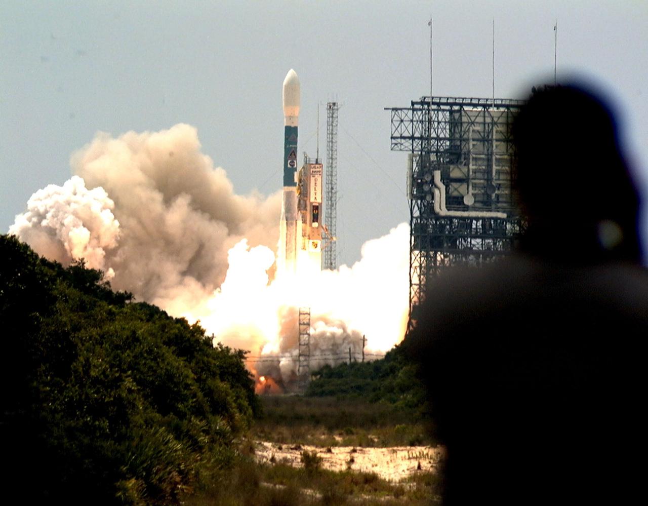 The shadow of a photographer (right) is caught watching the perfect launch of the Boeing Delta II rocket in the background after it lifted off at 11:44 a.m. EDT. The rocket carries NASA's Far Ultraviolet Spectroscopic Explorer (FUSE) satellite, which was developed to investigate the origin and evolution of the lightest elements in the universe hydrogen and deuterium. In addition, the FUSE satellite will examine the forces and process involved in the evolution of the galaxies, stars and planetary systems by investigating light in the far ultraviolet portion of the electromagnetic spectrum