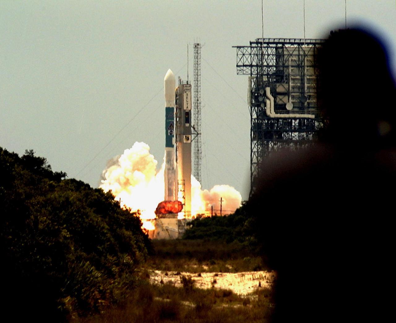 KENNEDY SPACE CENTER, FLA. -- A fireball erupts under the Boeing Delta II rocket, amid clouds of smoke and steam, as it lifts off from Launch Pad 17A, Cape Canaveral Air Station, at 11:44 a.m. EDT. The shadow of a photographer (right) is caught watching the perfect launch. The rocket carries NASA's Far Ultraviolet Spectroscopic Explorer (FUSE) satellite, which was developed to investigate the origin and evolution of the lightest elements in the universe hydrogen and deuterium. In addition, the FUSE satellite will examine the forces and process involved in the evolution of the galaxies, stars and planetary systems by investigating light in the far ultraviolet portion of the electromagnetic spectrum