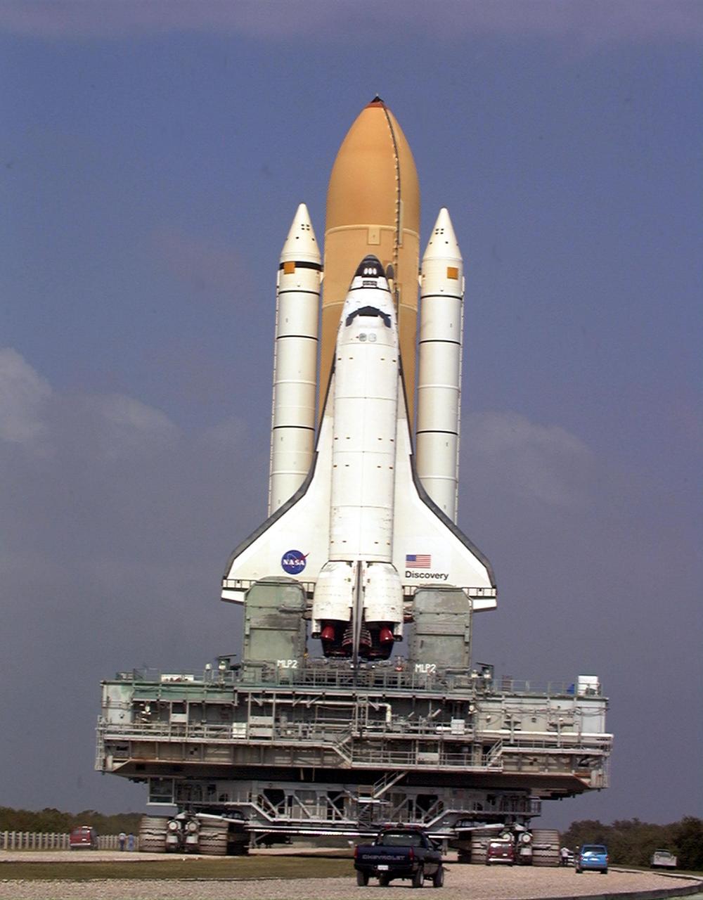 KENNEDY SPACE CENTER, FLA. -- Towering atop the mobile launcher platform and crawler transporter, Space Shuttle Discovery negotiates a turn in the crawlerway on its trek from the Vehicle Assembly Building to Launch Pad 39B. While at the pad, the orbiter, external tank and solid rocket boosters will undergo final preparations for the STS-103 launch targeted for Dec. 6, 1999, at 2:37 a.m. EST. The mission is a "call-up" due to the need to replace portions of the pointing system the gyros which have begun to fail on the Hubble Space Telescope. Although Hubble is operating normally and conducting its scientific observations, only three of its six gyroscopes are working properly. The gyroscopes allow the telescope to point at stars, galaxies and planets. The STS-103 crew will also be installing a Fine Guidance Sensor, a new enhanced computer, a solid-state digital recorder, and a new spare transmitter to replace older equipment, and replacing degraded insulation on the telescope with new thermal insulation. The crew will also install a Battery Voltage/Temperature Improvement Kit to protect the spacecraft batteries from overcharging and overheating when the telescope goes into a safe mode. Four EVA's are planned to make the necessary repairs and replacements on the telescope. The STS-103 crew members are Commander Curtis L. Brown Jr., Pilot Scott J. Kelly, Mission Specialist Steven L. Smith, Mission Specialist C. Michael Foale (Ph.D.), Mission Specialist John M. Grunsfeld (Ph.D.), and Mission Specialist Claude Nicollier of Switzerland, and Mission Specialist Jean-François Clervoy of France, both with the European Space Agency