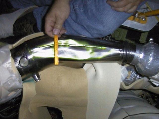 KENNEDY SPACE CENTER, FLA. -- A small ruler shows the relative size of the bent LH2 recirculation line in Space Shuttle Discovery's engine compartment. Underneath the line is material draped to protect other components. The 12-inch-long dent was discovered during routine aft compartment inspections Tuesday, Dec. 7. The LH2 line recirculates hydrogen from the Shuttle main engines back to the external tank during prelaunch engine conditioning. The line is being replaced and managers expect the replacement work to take about 3 days, followed by system retests and final aft compartment close-outs. Preliminary assessments reflect a launch date of Space Shuttle Discovery on mission STS-103 no earlier than Dec. 16. STS-103 is the third servicing mission for the Hubble Space Telescope