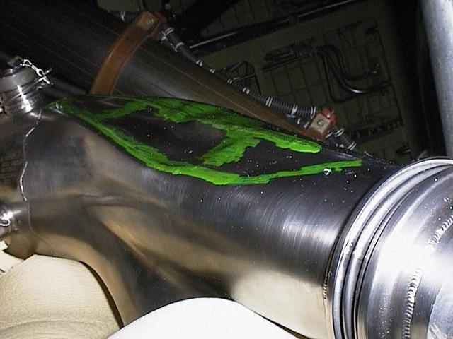 KENNEDY SPACE CENTER, FLA. -- Green dye penetrant helps pinpoint the dent discovered in this LH2 recirculation line in Space Shuttle Discovery's engine compartment. The 12-inch-long dent was discovered during routine aft compartment inspections Tuesday, Dec. 7. The LH2 line recirculates hydrogen from the Shuttle main engines back to the external tank during prelaunch engine conditioning. The line is being replaced and managers expect the replacement work to take about 3 days, followed by system retests and final aft compartment close-outs. Preliminary assessments reflect a launch date of Space Shuttle Discovery on mission STS-103 no earlier than Dec. 16. STS-103 is the third servicing mission for the Hubble Space Telescope