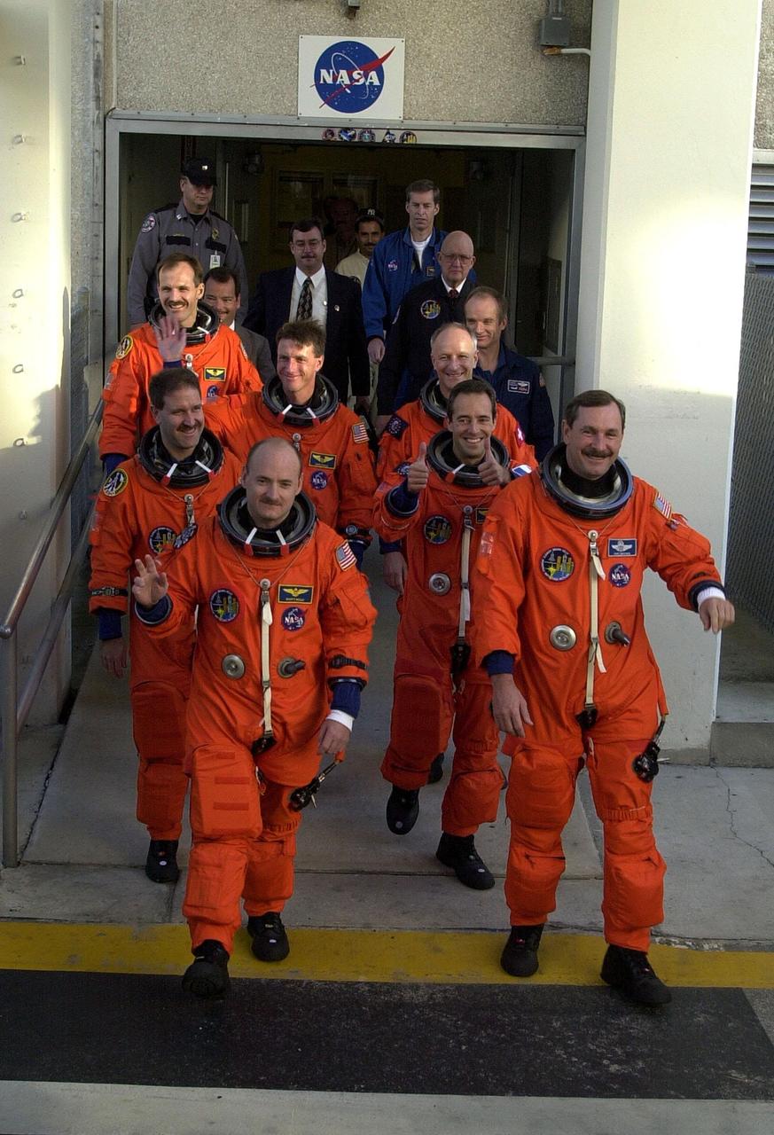 For the second time in two days, the STS-103 crew in their launch and entry suits eagerly head out of the Operations and Checkout Building on their way to Launch Pad 39B and liftoff of Space Shuttle Discovery. From front to back by two's are Pilot Scott J. Kelly and Commander Curtis L. Brown Jr., Mission Specialists John M. Grunsfeld (Ph.D.) and Jean-Francois Clervoy of France, C. Michael Foale (Ph.D.) and Claude Nicollier of Switzerland, and Steven L. Smith taking up the rear. The previous launch attempt on Dec. 17 was scrubbed about 8:52 p.m. due to numerous violations of weather launch commit criteria at KSC. The mission, to service the Hubble Space Telescope, is now scheduled for launch Dec. 19 at 7:50 p.m. EST from Launch Pad 39B. Mission objectives include replacing gyroscopes and an old computer, installing another solid state recorder, and replacing damaged insulation in the telescope. After the 7-day, 21-hour mission, Discovery is expected to land at KSC Monday, Dec. 27, at about 5:24 p.m. EST