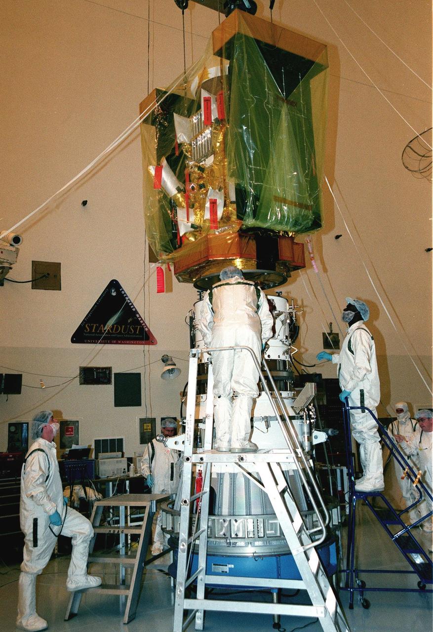 In the Payload Hazardous Servicing Facility, workers help guide the spacecraft Stardust being lowered in order to mate it with the third stage of a Boeing Delta II rocket. Targeted for launch Feb. 6 from Launch Pad 17-A, Cape Canaveral Air Station, aboard the Delta II rocket, the spacecraft is destined for a close encounter with the comet Wild 2 in January 2004. Using a silicon-based substance called aerogel, Stardust will capture comet particles flying off the nucleus of the comet. The spacecraft also will bring back samples of interstellar dust. These materials consist of ancient pre-solar interstellar grains and other remnants left over from the formation of the solar system. Scientists expect their analysis to provide important insights into the evolution of the sun and planets and possibly into the origin of life itself. The collected samples will return to Earth in a sample return capsule to be jettisoned as Stardust swings by Earth in January 2006