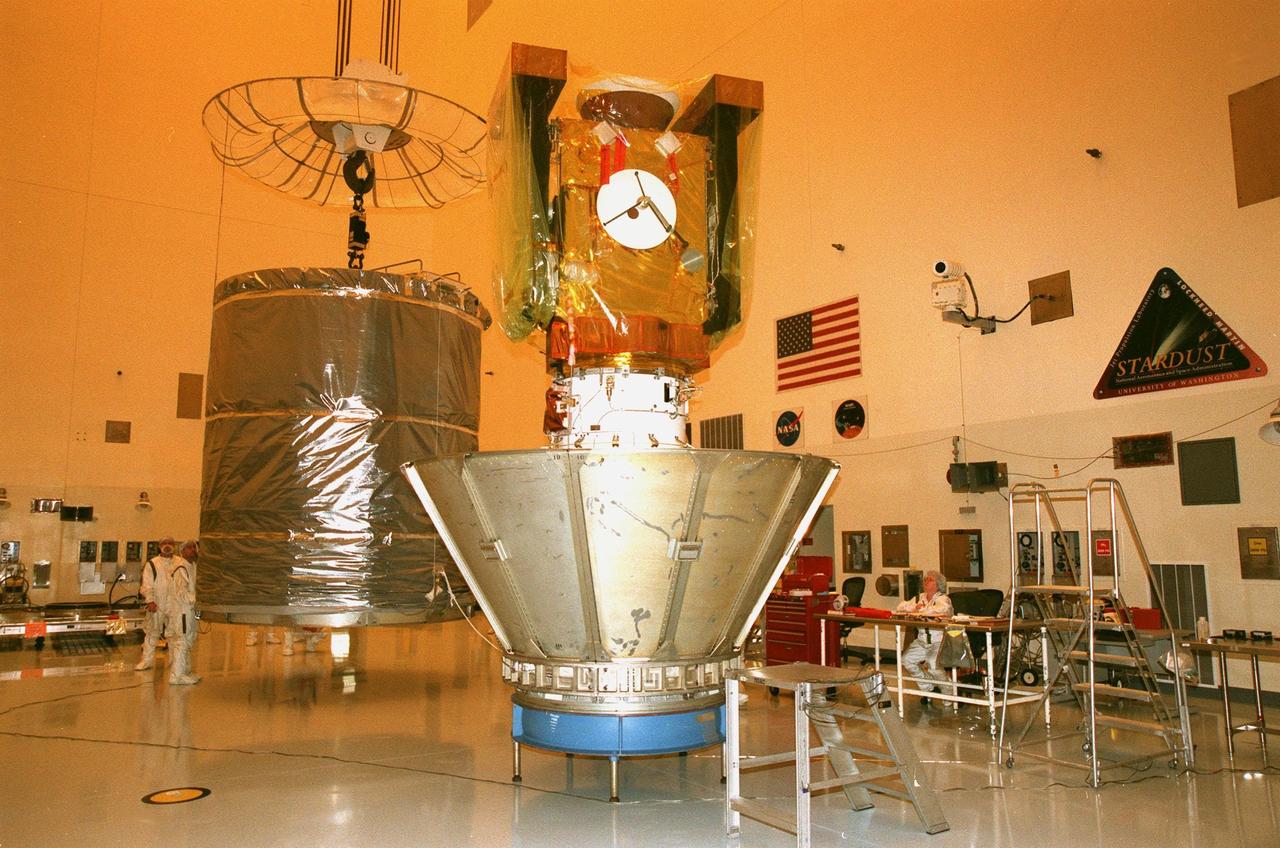 In the Payload Hazardous Servicing Facility, a canister (left) is moved toward the Stardust spacecraft (right). The protective canister will enclose Stardust before the spacecraft is moved to Launch Pad 17-A, Cape Canaveral Air Station, for launch preparations. Stardust is targeted for liftoff on Feb. 6 aboard a Boeing Delta II rocket for a close encounter with the comet Wild 2 in January 2004. Using a silicon-based substance called aerogel, Stardust will capture comet particles flying off the nucleus of the comet. The spacecraft also will bring back samples of interstellar dust. These materials consist of ancient pre-solar interstellar grains and other remnants left over from the formation of the solar system. Scientists expect their analysis to provide important insights into the evolution of the sun and planets and possibly into the origin of life itself. The collected samples will return to Earth in a sample return capsule to be jettisoned as Stardust swings by Earth in January 2006