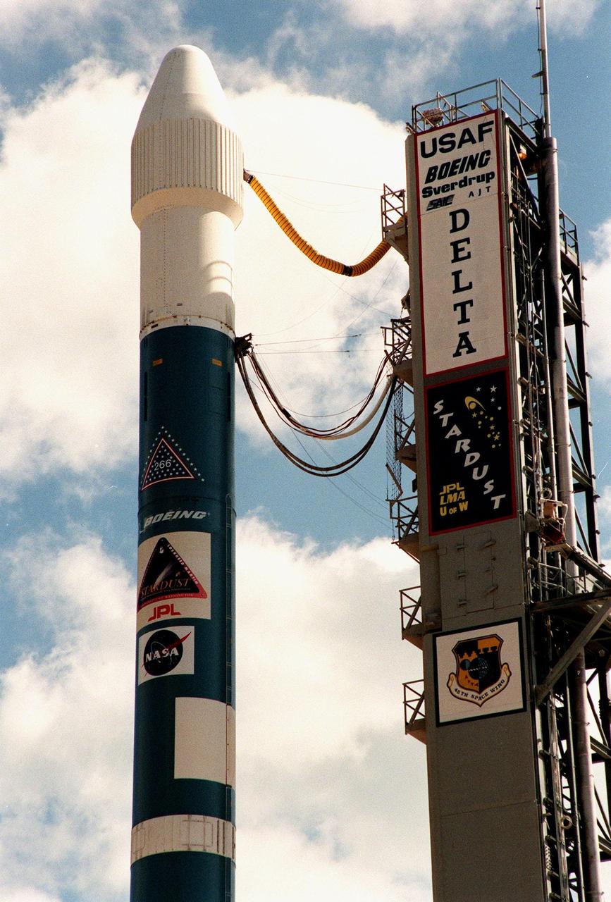 At Launch Pad 17-A, Cape Canaveral Air Station, a Boeing Delta II rocket is poised for liftoff after tower rollback. Umbilical lines (at top) still attached to the fixed utility tower (at right) feed electricity, air conditioning and coolants for the Stardust spacecraft inside the fairing (enclosing the upper stage) before launch. The targeted launch time is 4:06 p.m. EST. Stardust is destined for a close encounter with the comet Wild 2 in January 2004. Using a silicon-based substance called aerogel, Stardust will capture comet particles flying off the nucleus of the comet. The spacecraft also will bring back samples of interstellar dust. These materials consist of ancient pre-solar interstellar grains and other remnants left over from the formation of the solar system. Scientists expect their analysis to provide important insights into the evolution of the sun and planets and possibly into the origin of life itself. The collected samples will return to Earth in a sample return capsule to be jettisoned as Stardust swings by Earth in January 2006