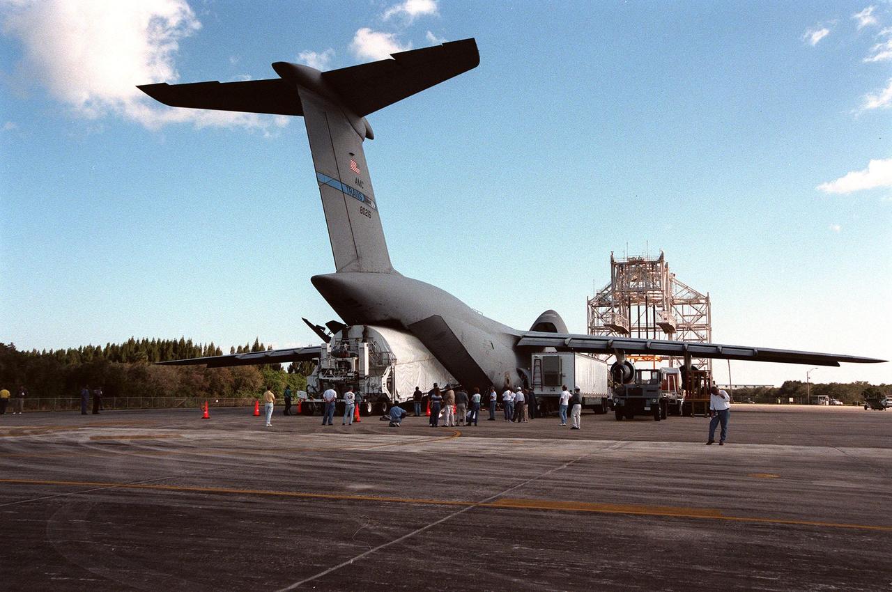 KENNEDY SPACE CENTER, FLA. -- The Chandra X-ray Observatory is unloaded from an Air Force C-5 Galaxy transporter two days after landing at the Shuttle Landing Facility on Feb. 4. The observatory sits cradled in the cargo hold of a tractor-trailer rig called the Space Cargo Transportation System, which closely resembles the size and shape of the Shuttle cargo bay. In the background (right) is the mate-demate device, used when an orbiter is returned to KSC on the back of a Shuttle carrier aircraft. Over the next few months, Chandra will undergo final tests and be mated to a Boeing-provided Inertial Upper Stage for launch July 9 aboard Space Shuttle Columbia, on mission STS-93 . Formerly called the Advanced X-ray Astrophysics Facility, Chandra comprises three major elements: the spacecraft, the science instrument module (SIM), and the world's most powerful X-ray telescope. Chandra will allow scientists from around the world to see previously invisible black holes and high-temperature gas clouds, giving the observatory the potential to rewrite the books on the structure and evolution of our universe