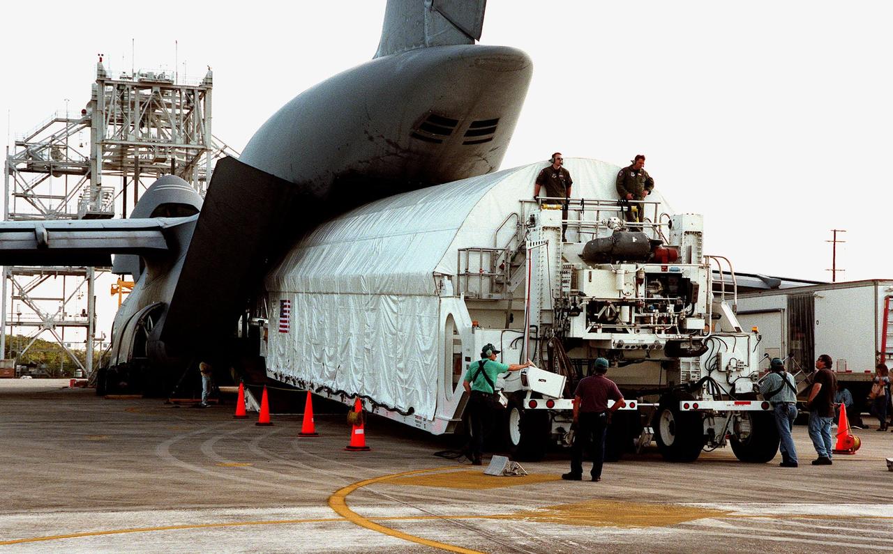 KENNEDY SPACE CENTER, FLA. -- The Chandra X-ray Observatory is unloaded from an Air Force C-5 Galaxy transporter two days after landing at the Shuttle Landing Facility on Feb. 4. The observatory sits cradled in the cargo hold of a tractor-trailer rig called the Space Cargo Transportation System, which closely resembles the size and shape of the Shuttle cargo bay. In the background (left) is the mate-demate device, used when an orbiter is returned to KSC on the back of a Shuttle carrier aircraft. Over the next few months, Chandra will undergo final tests and be mated to a Boeing-provided Inertial Upper Stage for launch July 9 aboard Space Shuttle Columbia, on mission STS-93 . Formerly called the Advanced X-ray Astrophysics Facility, Chandra comprises three major elements: the spacecraft, the science instrument module (SIM), and the world's most powerful X-ray telescope. Chandra will allow scientists from around the world to see previously invisible black holes and high-temperature gas clouds, giving the observatory the potential to rewrite the books on the structure and evolution of our universe