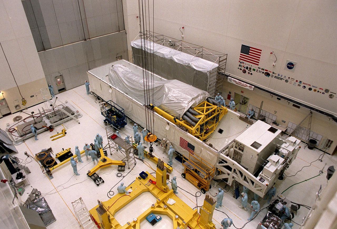 Inside the Vertical Processing Facility (VPF), the Chandra X-ray Observatory (top) lies in its protective container while workers on the floor prepare the overhead cable that will remove it. In the VPF, the telescope will undergo final installation of associated electronic components; it will also be tested, fueled and mated with the Inertial Upper Stage booster. A set of integrated tests will follow. Chandra is scheduled for launch July 9 aboard Space Shuttle Columbia, on mission STS-93 . Formerly called the Advanced X-ray Astrophysics Facility, Chandra comprises three major elements: the spacecraft, the science instrument module (SIM), and the world's most powerful X-ray telescope. Chandra will allow scientists from around the world to see previously invisible black holes and high-temperature gas clouds, giving the observatory the potential to rewrite the books on the structure and evolution of our universe