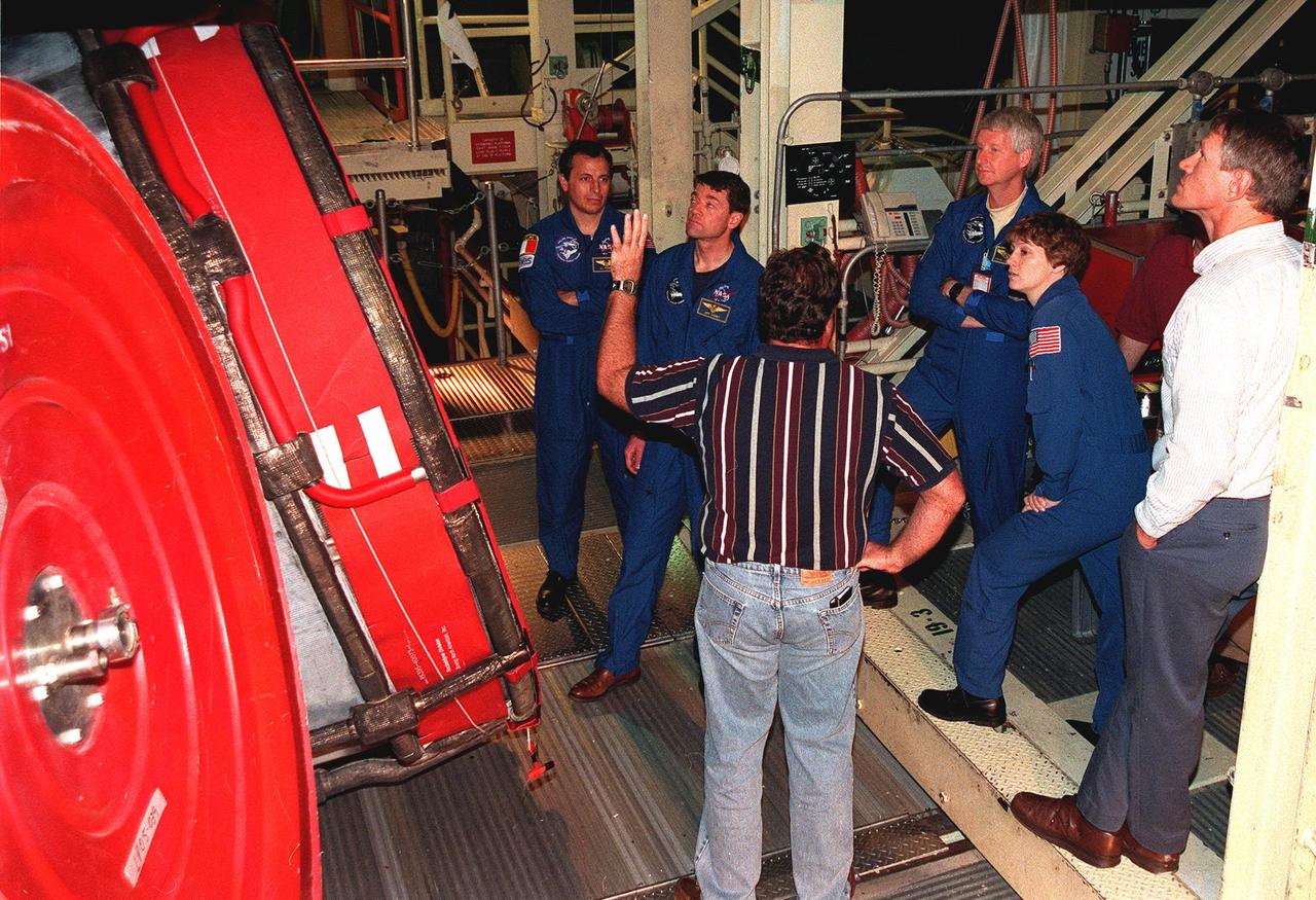 Members of the STS-93 crew look over the Space Shuttle Columbia's main engine in the Space Shuttle Main Engine Facility as they listen to Al Strainer, with United Space Alliance. From left, the crew members are Mission Specialist Michel Tognini of France, who represents the Centre National d'Etudes Spatiales (CNES), Pilot Jeffrey S. Ashby, Mission Specialist Steven A. Hawley, and Commander Eileen Collins. At the far right is Matt Gaetjens, with the Vehicle Integration Test Team. The fifth crew member (not shown) is Mission Specialist Catherine G. Coleman. STS-93, scheduled to launch July 9, has the primary mission of the deployment of the Chandra X-ray Observatory. Formerly called the Advanced X-ray Astrophysics Facility, Chandra comprises three major elements: the spacecraft, the science instrument module (SIM), and the world's most powerful X-ray telescope. Chandra will allow scientists from around the world to see previously invisible black holes and high-temperature gas clouds, giving the observatory the potential to rewrite the books on the structure and evolution of our universe