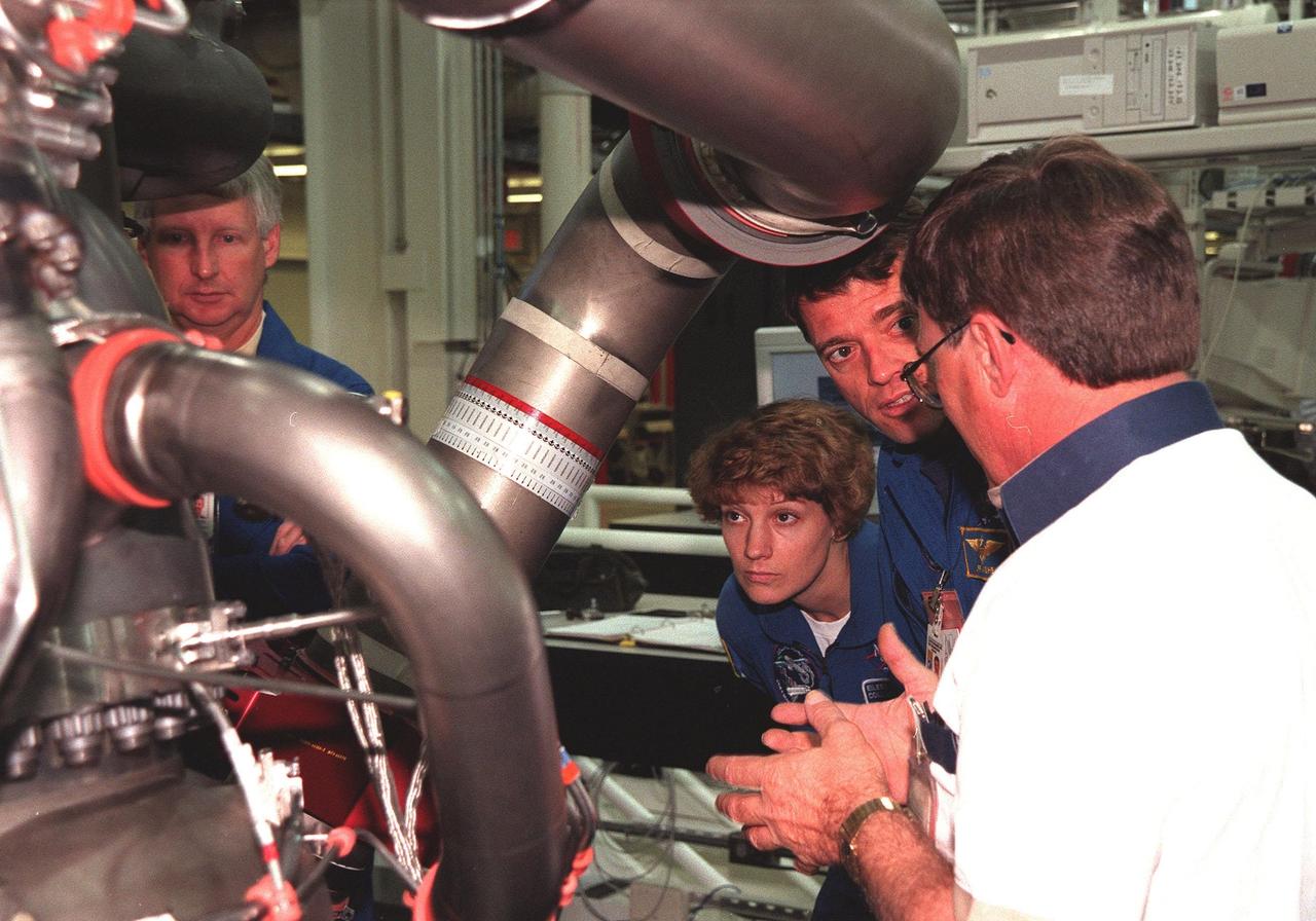 In the Space Shuttle Main Engine Facility, STS-93 crew members listen to Site Director Dan Hausman, with Rocketdyne, while looking over the main engine of the Space Shuttle Columbia. From left, they are Mission Specialist Steven A. Hawley, Commander Eileen Collins and Pilot Jeffrey S. Ashby. Other crew members (not shown) are Mission Specialist Michel Tognini of France, who represents the Centre National d'Etudes Spatiales (CNES), and Mission Specialist Catherine G. Coleman. STS-93, scheduled to launch July 9 aboard Space Shuttle Columbia, has the primary mission of the deployment of the Chandra X-ray Observatory. Formerly called the Advanced X-ray Astrophysics Facility, Chandra comprises three major elements: the spacecraft, the science instrument module (SIM), and the world's most powerful X-ray telescope. Chandra will allow scientists from around the world to see previously invisible black holes and high-temperature gas clouds, giving the observatory the potential to rewrite the books on the structure and evolution of our universe