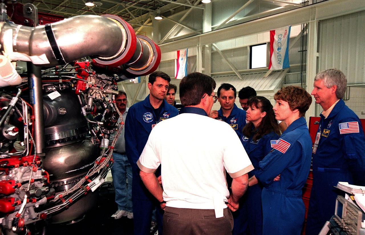 In the Space Shuttle Main Engine Facility, , STS-93 crew members listen to Site Director Dan Hausman, with Rocketdyne, while looking over the main engine of the Space Shuttle Columbia. From left, they are Pilot Jeffrey S. Ashby, Mission Specialists Michel Tognini of France, who represents the Centre National d'Etudes Spatiales (CNES), and Mission Specialist Catherine G. Coleman, Commander Eileen Collins and Mission Specialist Steven A. Hawley. STS-93, scheduled to launch July 9 aboard Space Shuttle Columbia, has the primary mission of the deployment of the Chandra X-ray Observatory. Formerly called the Advanced X-ray Astrophysics Facility, Chandra comprises three major elements: the spacecraft, the science instrument module (SIM), and the world's most powerful X-ray telescope. Chandra will allow scientists from around the world to see previously invisible black holes and high-temperature gas clouds, giving the observatory the potential to rewrite the books on the structure and evolution of our universe