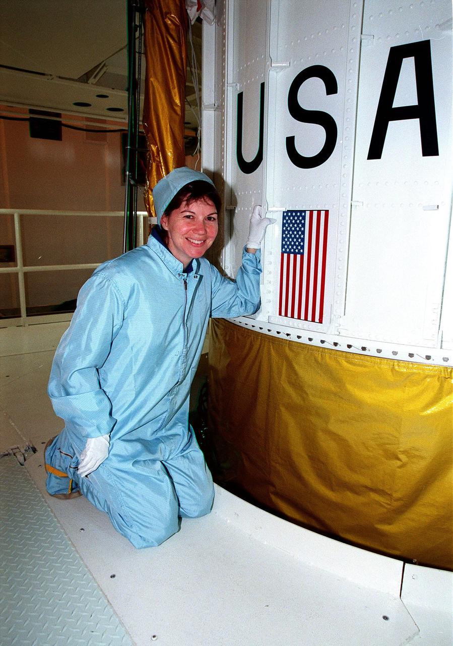 In the Solid Motor Assembly Building, Cape Canaveral Air Station, STS-93 Mission Specialist Catherine G. Coleman kneels next to the Inertial Upper Stage booster being readied for the mission. Other crew members (not shown) are Commander Eileen Collins, Pilot Jeffrey S. Ashby and Mission Specialists Steven A. Hawley and Michel Tognini of France, who represents the Centre National d'Etudes Spatiales (CNES). STS-93, scheduled to launch July 9 aboard Space Shuttle Columbia, has the primary mission of the deployment of the Chandra X-ray Observatory. Formerly called the Advanced X-ray Astrophysics Facility, Chandra comprises three major elements: the spacecraft, the science instrument module (SIM), and the world's most powerful X-ray telescope. Chandra will allow scientists from around the world to see previously invisible black holes and high-temperature gas clouds, giving the observatory the potential to rewrite the books on the structure and evolution of our universe
