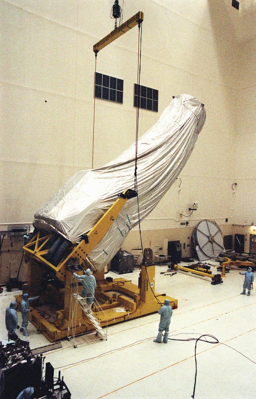 In the Vertical Processing Facility (VPF), workers keep watch on the crane lifting the shrouded Chandra X-ray Observatory to a vertical position. The telescope will undergo final installation of associated electronic components; it will also be tested, fueled and mated with the Inertial Upper Stage booster. A set of integrated tests will follow. Chandra is scheduled for launch July 9 aboard Space Shuttle Columbia, on mission STS-93 . Formerly called the Advanced X-ray Astrophysics Facility, Chandra comprises three major elements: the spacecraft, the science instrument module (SIM), and the world's most powerful X-ray telescope. Chandra will allow scientists from around the world to see previously invisible black holes and high-temperature gas clouds, giving the observatory the potential to rewrite the books on the structure and evolution of our universe