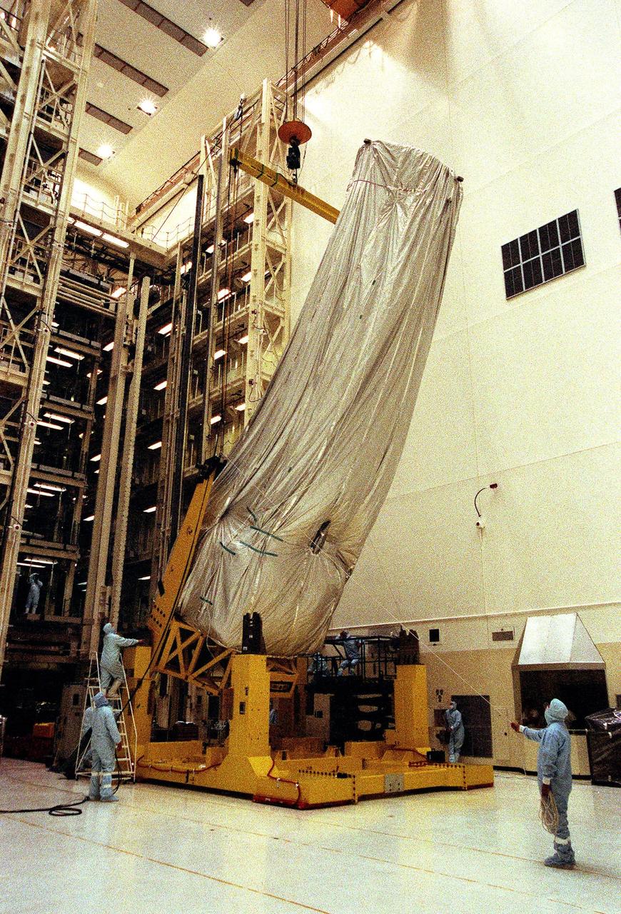 In the Vertical Processing Facility (VPF), workers guide the final stages as the overhead crane lifts the shrouded Chandra X-ray Observatory to a vertical position. The telescope will undergo final installation of associated electronic components; it will also be tested, fueled and mated with the Inertial Upper Stage booster. A set of integrated tests will follow. Chandra is scheduled for launch July 9 aboard Space Shuttle Columbia, on mission STS-93 . Formerly called the Advanced X-ray Astrophysics Facility, Chandra comprises three major elements: the spacecraft, the science instrument module (SIM), and the world's most powerful X-ray telescope. Chandra will allow scientists from around the world to see previously invisible black holes and high-temperature gas clouds, giving the observatory the potential to rewrite the books on the structure and evolution of our universe