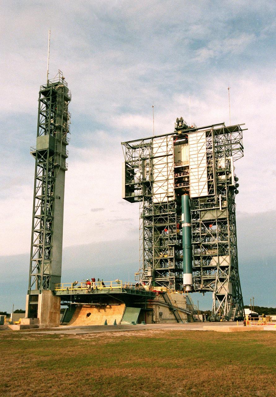 The first stage of a Boeing Delta II rocket is in position on the mobile tower (at right) at Launch Complex 17. At left is the launch tower. The rocket will carry the Stardust spacecraft into space for a close encounter with the comet Wild 2 in January 2004. Using a medium called aerogel, it will capture comet particles flying off the nucleus of the comet, plus collect interstellar dust for later analysis. The collected samples will return to Earth in a Sample Return Capsule to be jettisoned as Stardust swings by Earth in January 2006. Stardust is scheduled to be launched on Feb. 6, 1999