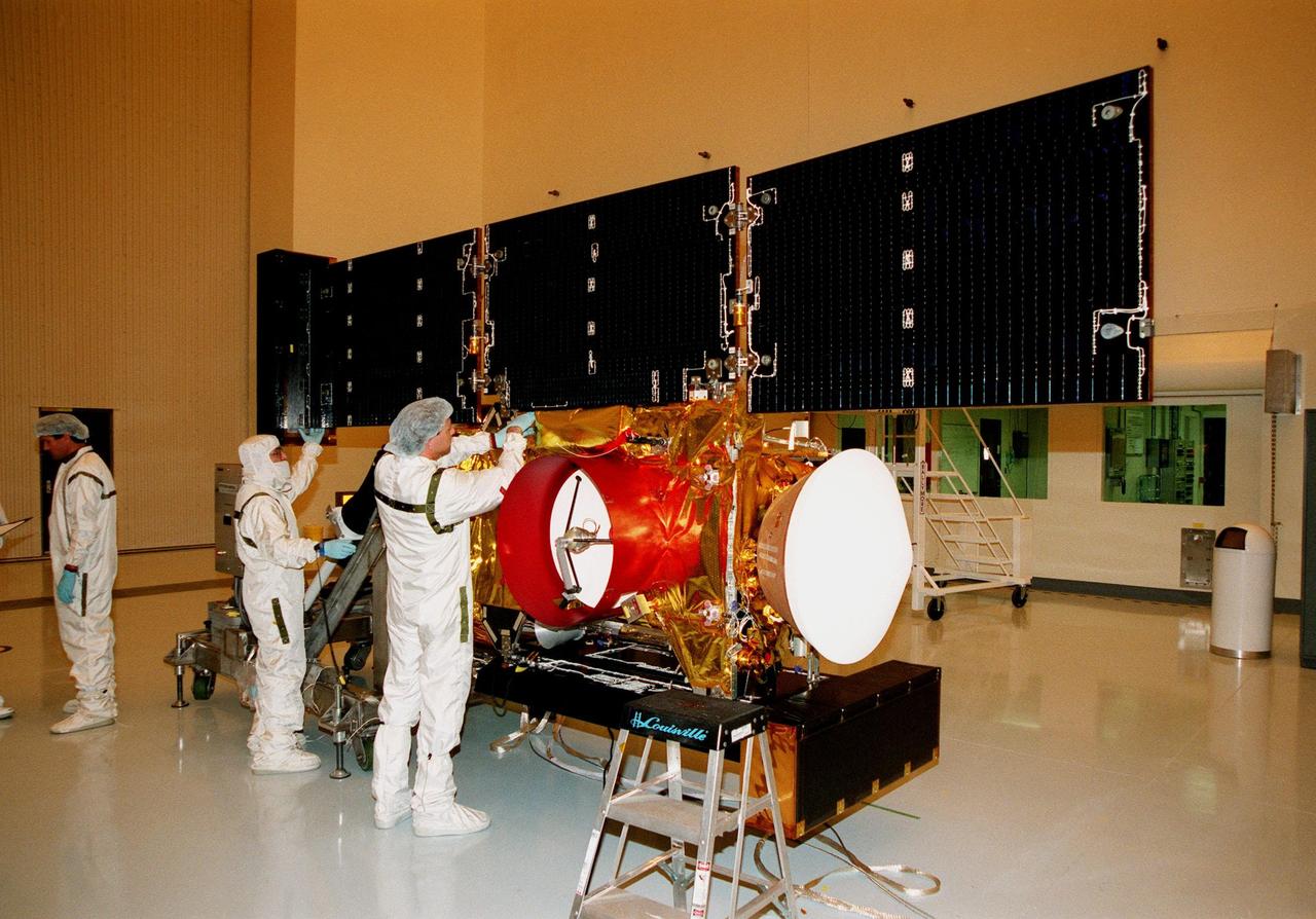 In the Payload Hazardous Servicing Facility, workers adjust the solar panels of the <a href="http://www-pao.ksc.nasa.gov/kscpao/captions/subjects/stardust.htm"> Stardust</a>spacecraft before performing lighting tests. Stardust is scheduled to be launched aboard a Boeing Delta II rocket from Launch Pad 17A, Cape Canaveral Air Station, on Feb. 6, 1999, for a rendezvous with the comet Wild 2 in January 2004. Stardust will use a substance called aerogel to capture comet particles flying off the nucleus of the comet, plus collect interstellar dust for later analysis. The collected samples will return to Earth in a sample return capsule to be jettisoned as it swings by Earth in January 2006