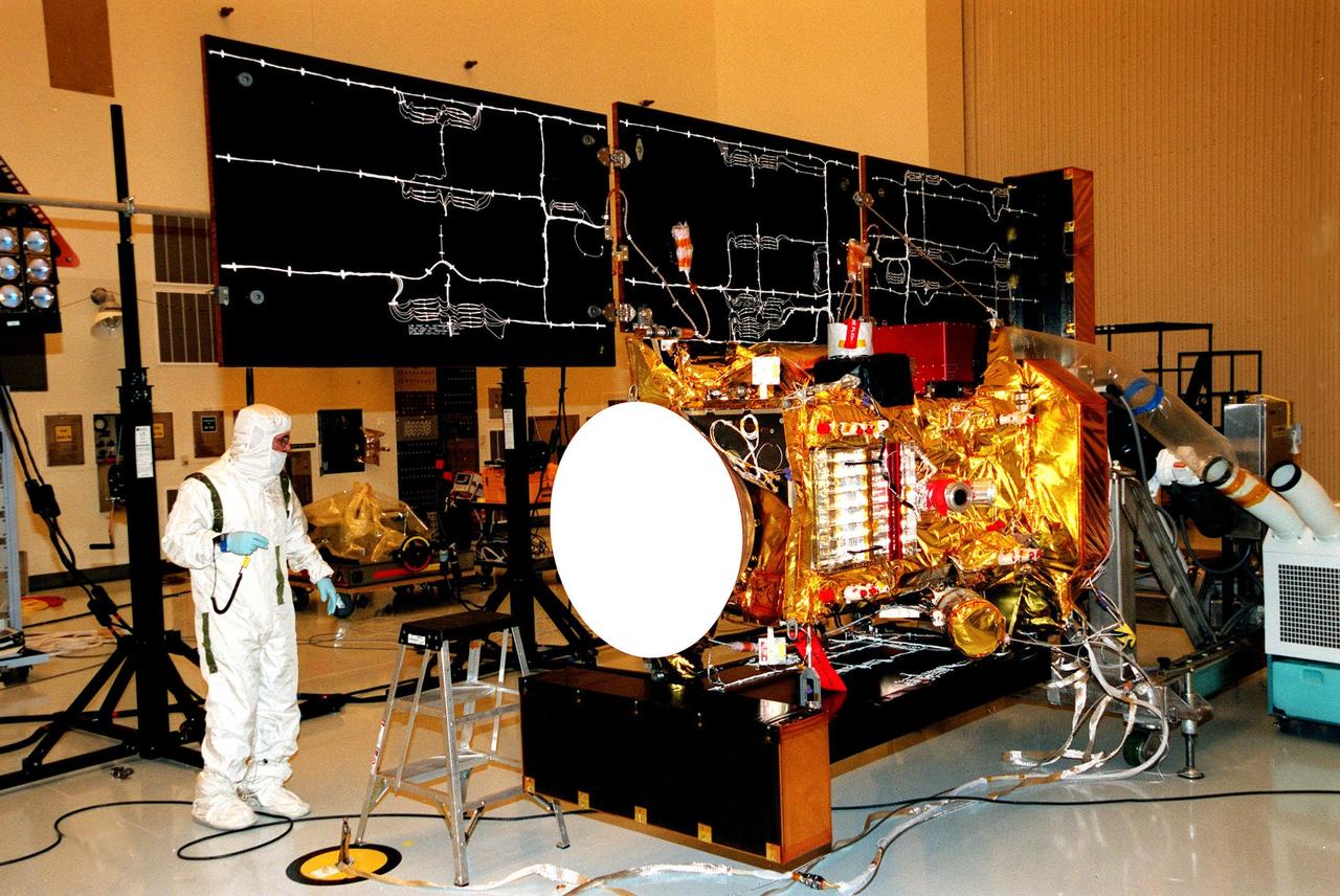 In the Payload Hazardous Servicing Facility, a worker looks over the solar panels of the <a href="http://www-pao.ksc.nasa.gov/kscpao/captions/subjects/stardust.htm"> Stardust</a> spacecraft before it undergoes lighting tests. Stardust is scheduled to be launched aboard a Boeing Delta II rocket from Launch Pad 17A, Cape Canaveral Air Station, on Feb. 6, 1999, for a rendezvous with the comet Wild 2 in January 2004. Stardust will use a substance called aerogel to capture comet particles flying off the nucleus of the comet, plus collect interstellar dust for later analysis. The collected samples will return to Earth in a sample return capsule (its white cap is seen on the left) to be jettisoned as it swings by Earth in January 2006